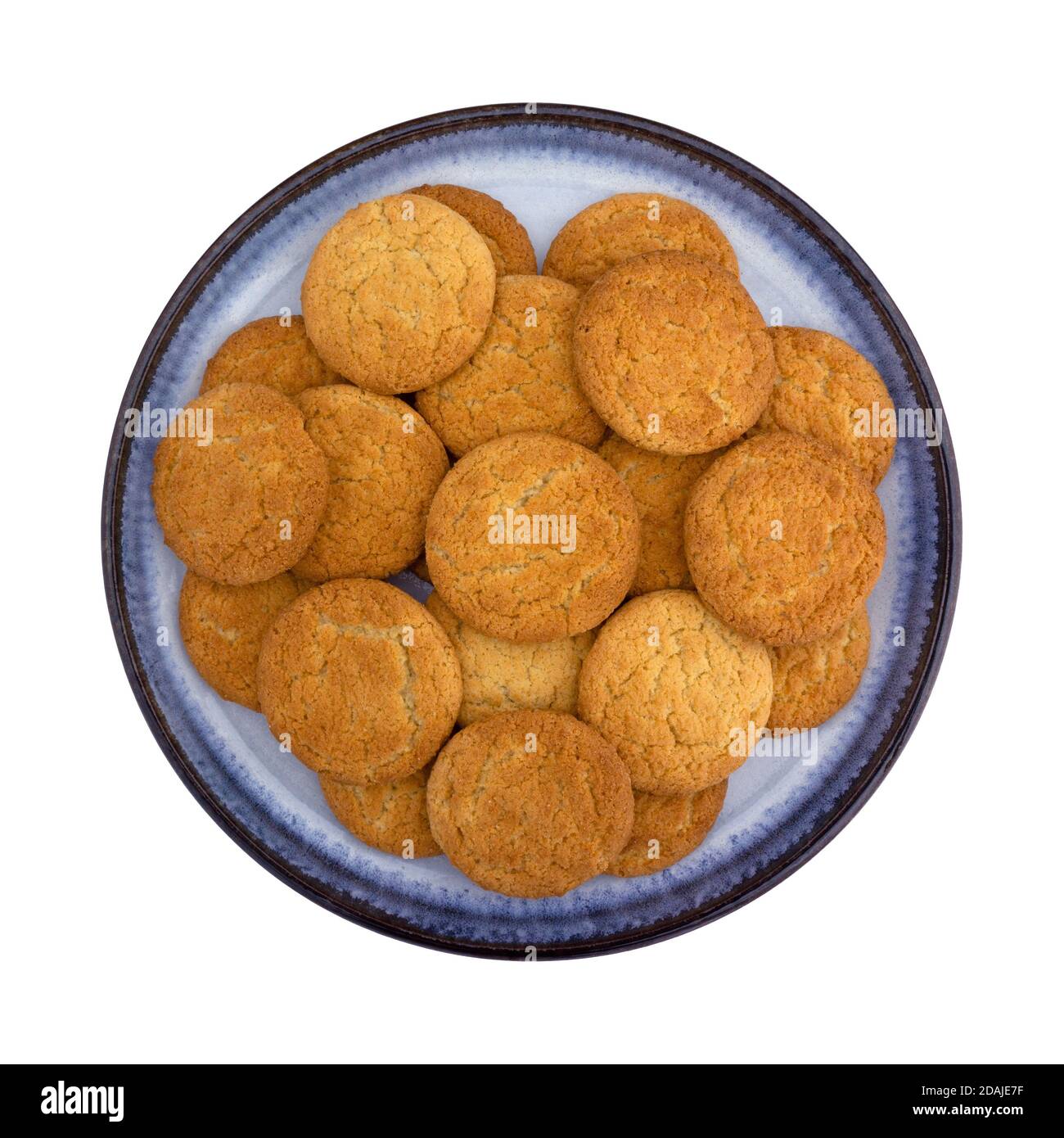 Top view of a group of coconut flavor cookies on a blue stoneware plate isolated on a white background. Stock Photo