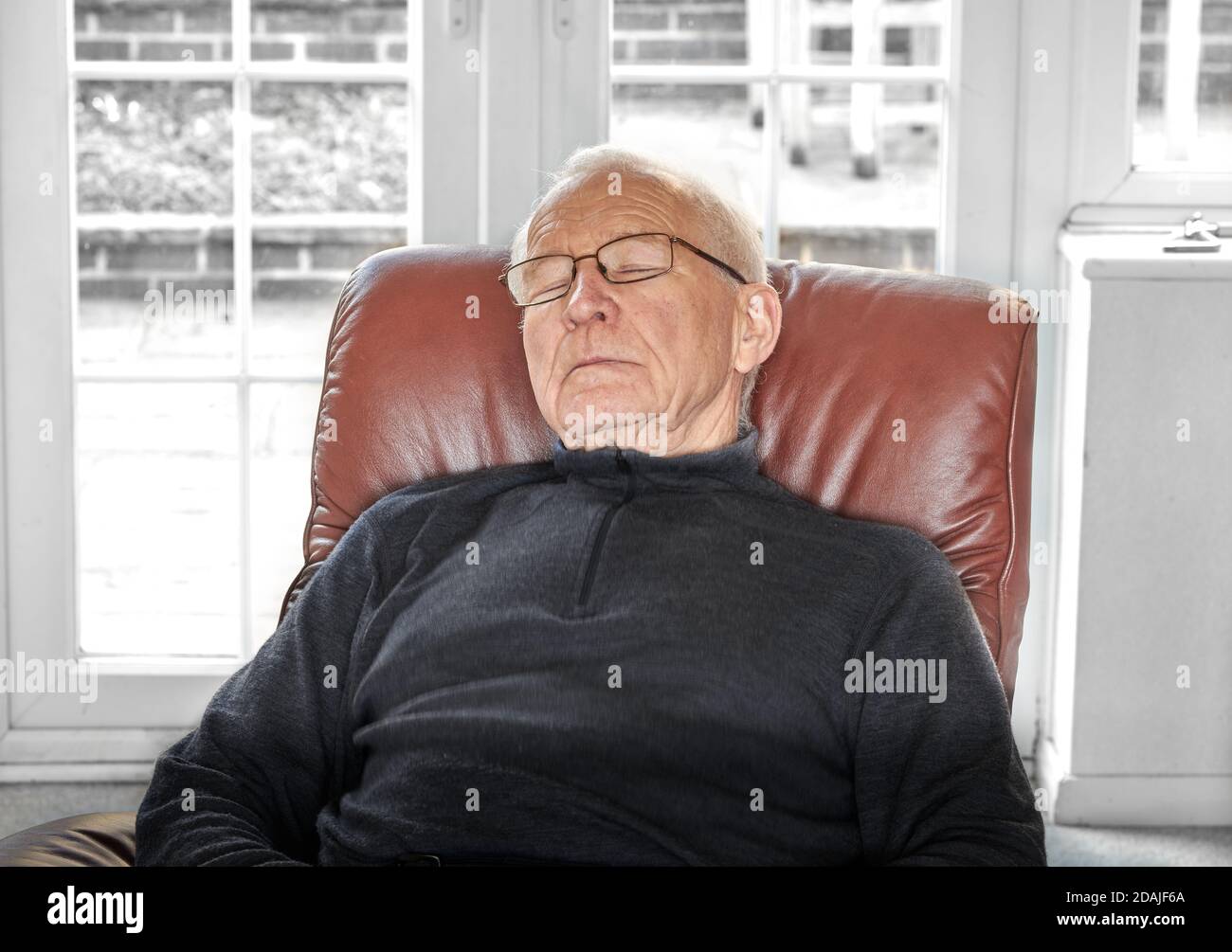 Elderly man in leather recliner chair takes a snooze. Stock Photo