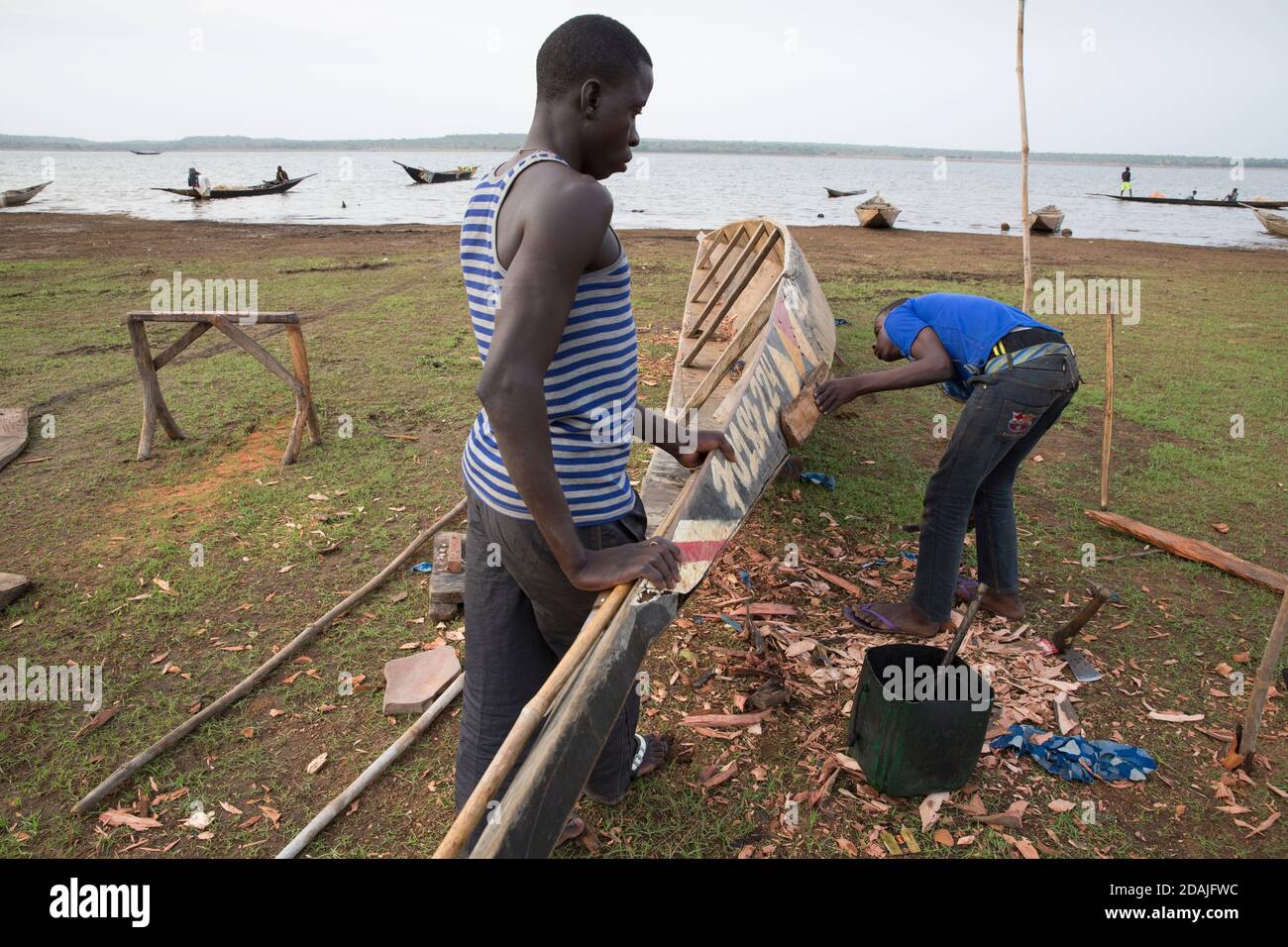 Selingue area, Mali, 27th April 2015; Boat builder and repairer, Ke Karonta, 17 (blue shirt) has never been to school.  His father is a boat builder and he is following in his father's footsteps. Stock Photo