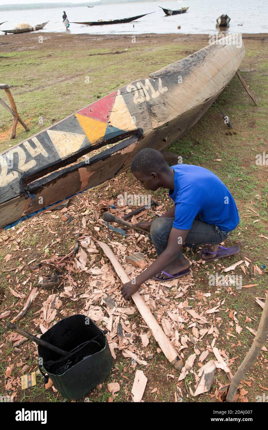 Selingue area, Mali, 27th April 2015; Boat builder and repairer, Ke Karonta, 17 (blue shirt) has never been to school.  His father is a boat builder and he is following in his father's footsteps. Stock Photo