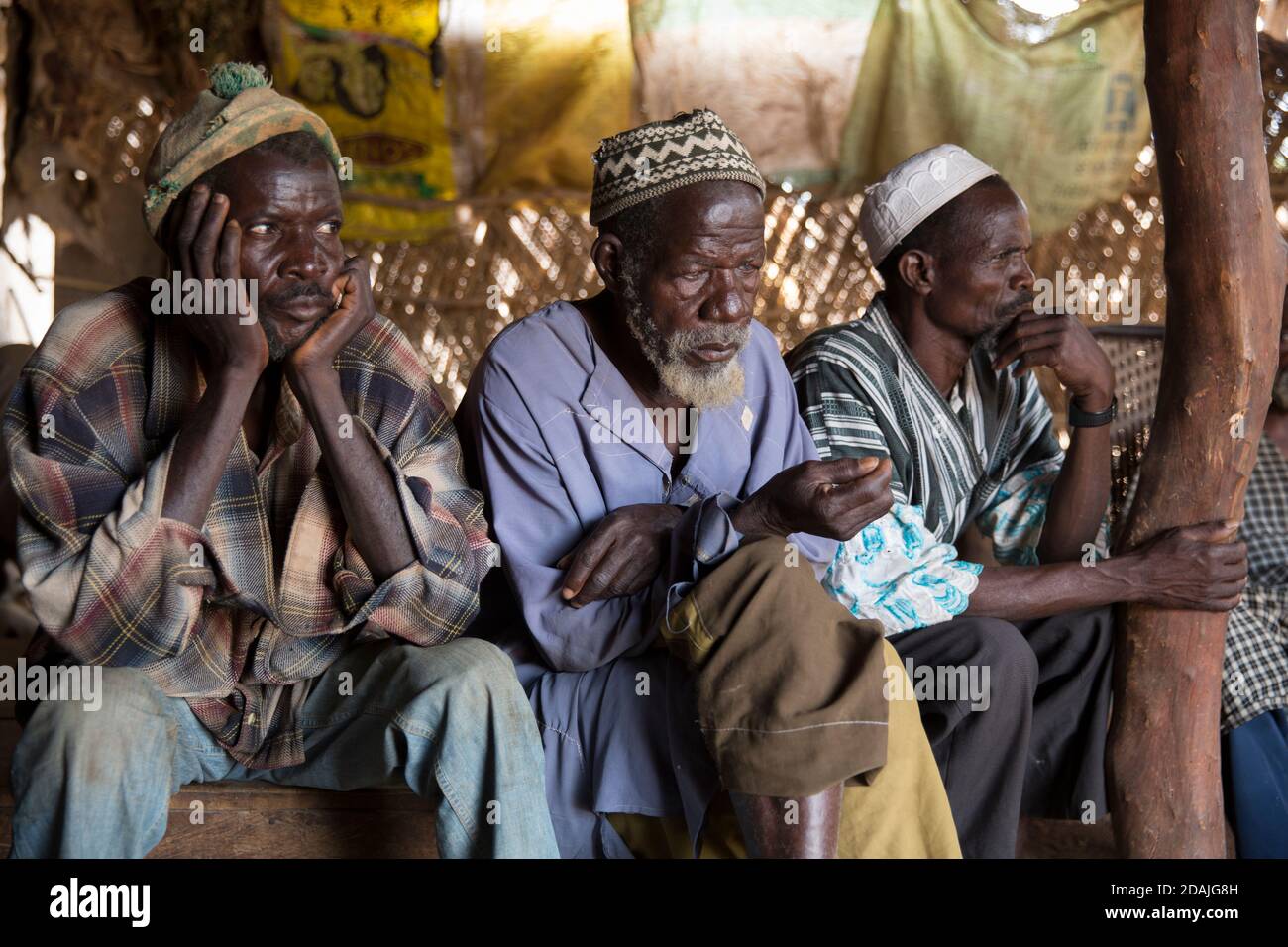 Delaba Koro, village 60 kms from Selingue, Mali, 27th April 2015; This village took many people displaced by the dam. Elders lister as  Oualama Doumbia, 56, speaks. He is a farmer, fisherman, hunter, and son of the previous chief. His expectations of the dam have not been met - he hoped for good health services, clean water, electricity and an overall improvement in agriculture, but 30 years later there is still no electricity, only one broken pump, the medical centre is not well equipped and there is only primary school for the children.  His family were amongst the village’s first settlers.  Stock Photo