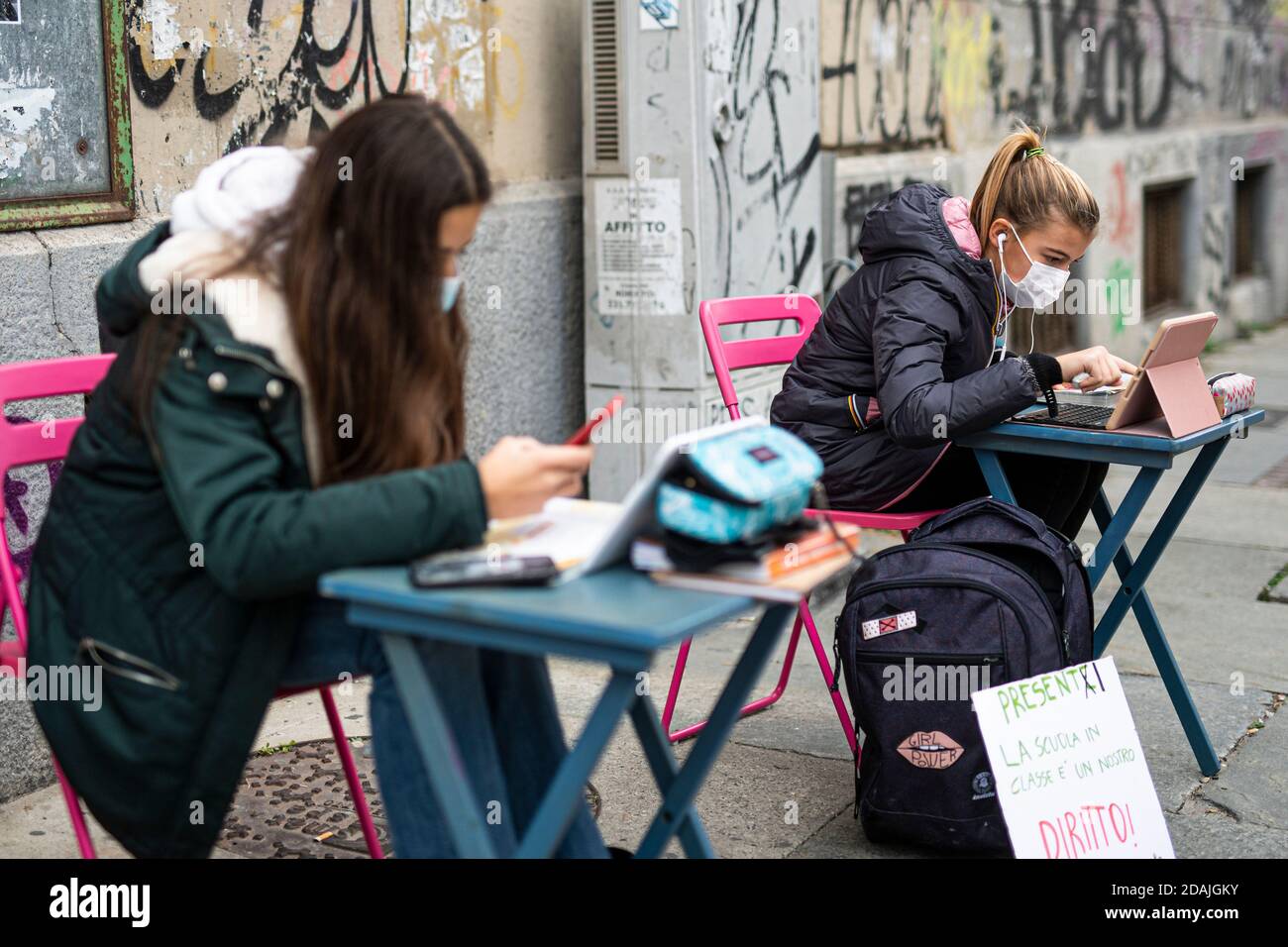 TURIN, ITALY - November 13, 2020: Two students of secondary school Calvino, called Anita and Lisa, follow a distance learning (DaD) lesson on the street outside their school to protest against schools closures imposed by the government due to an increase in COVID-19 coronavirus disease infections. Anita has been protesting every school day since November 6 when Piedmont became a red zone, a day later Lisa joined her. On November 11 Anita received a solidarity call from the Italian Minister of Education Lucia Azzolina. (Photo by Nicol Stock Photo