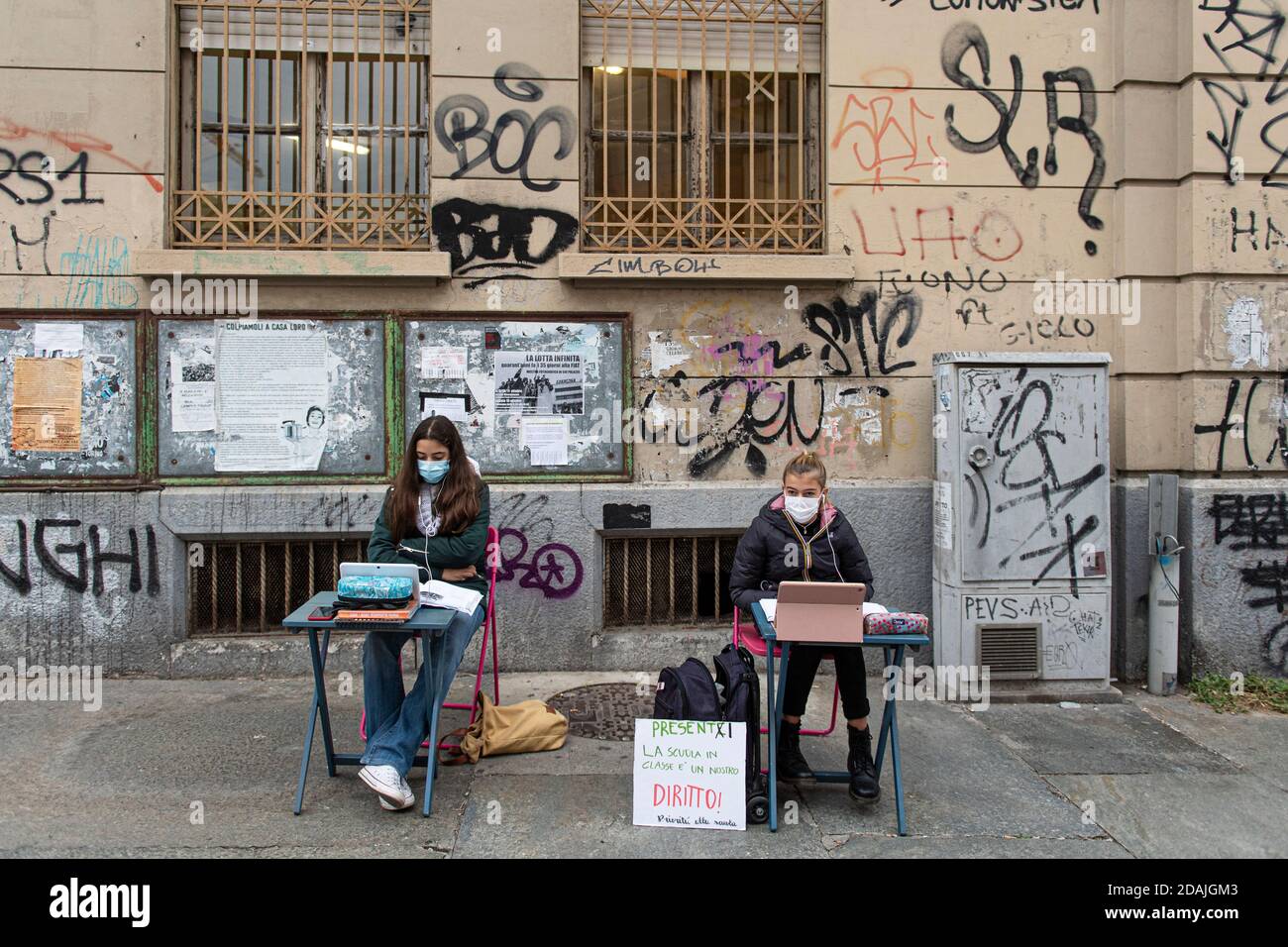 TURIN, ITALY - November 13, 2020: Two students of secondary school Calvino, called Anita (R) and Lisa, follow a distance learning (DaD) lesson on the street outside their school to protest against schools closures imposed by the government due to an increase in COVID-19 coronavirus disease infections. Anita has been protesting every school day since November 6 when Piedmont became a red zone, a day later Lisa joined her. On November 11 Anita received a solidarity call from the Italian Minister of Education Lucia Azzolina. (Photo by Nicol Stock Photo