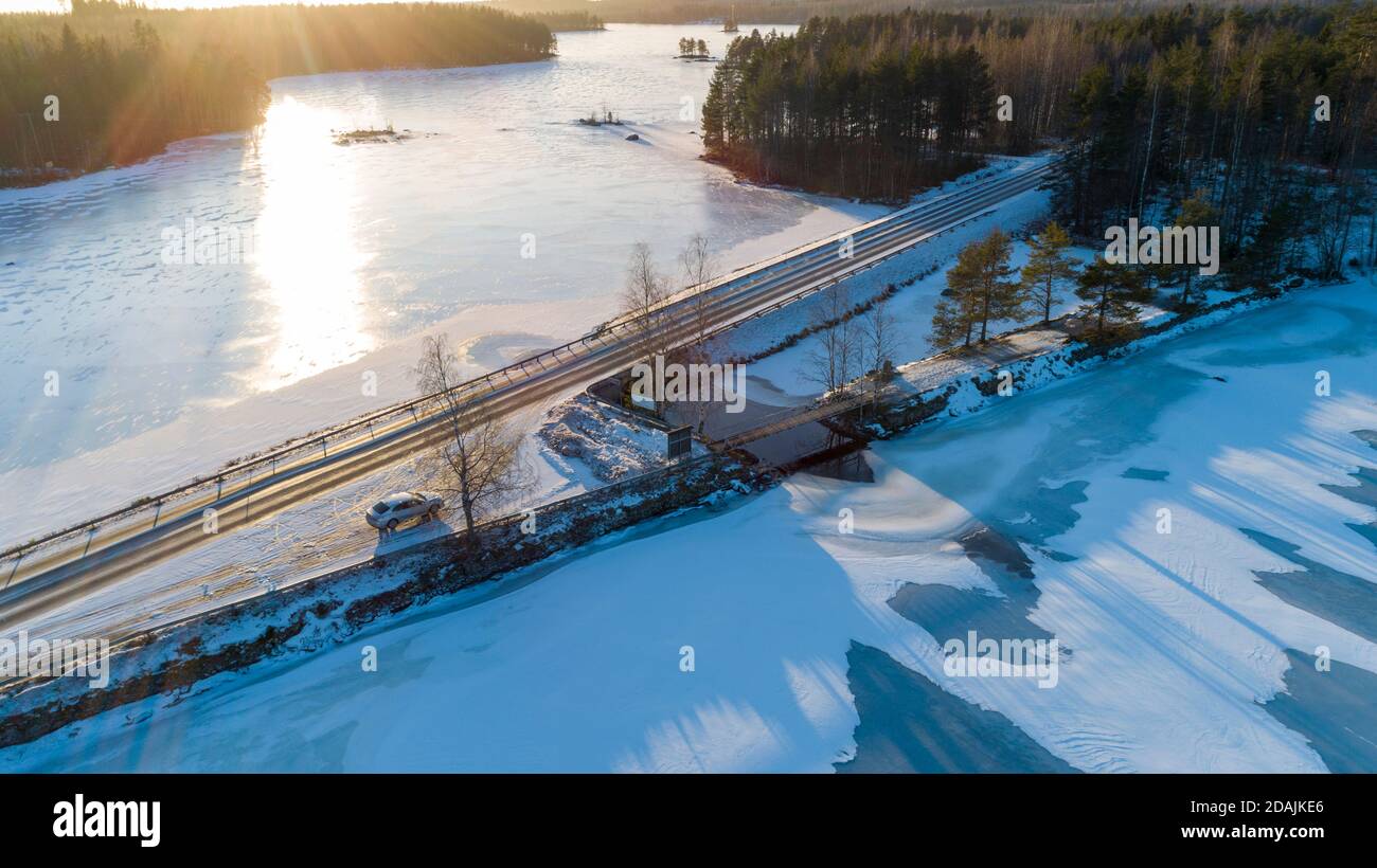 Aerial view of highway causeway and car at layby at Timosensalmi strait between frozen lakes Pohjois-Konnevesi and Etelä-Konnevesi at Winter , Finland Stock Photo
