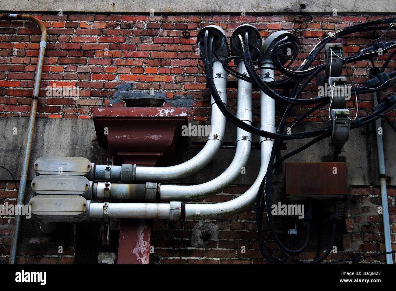 This old weathered red brick wall is supporting a hub of industrial