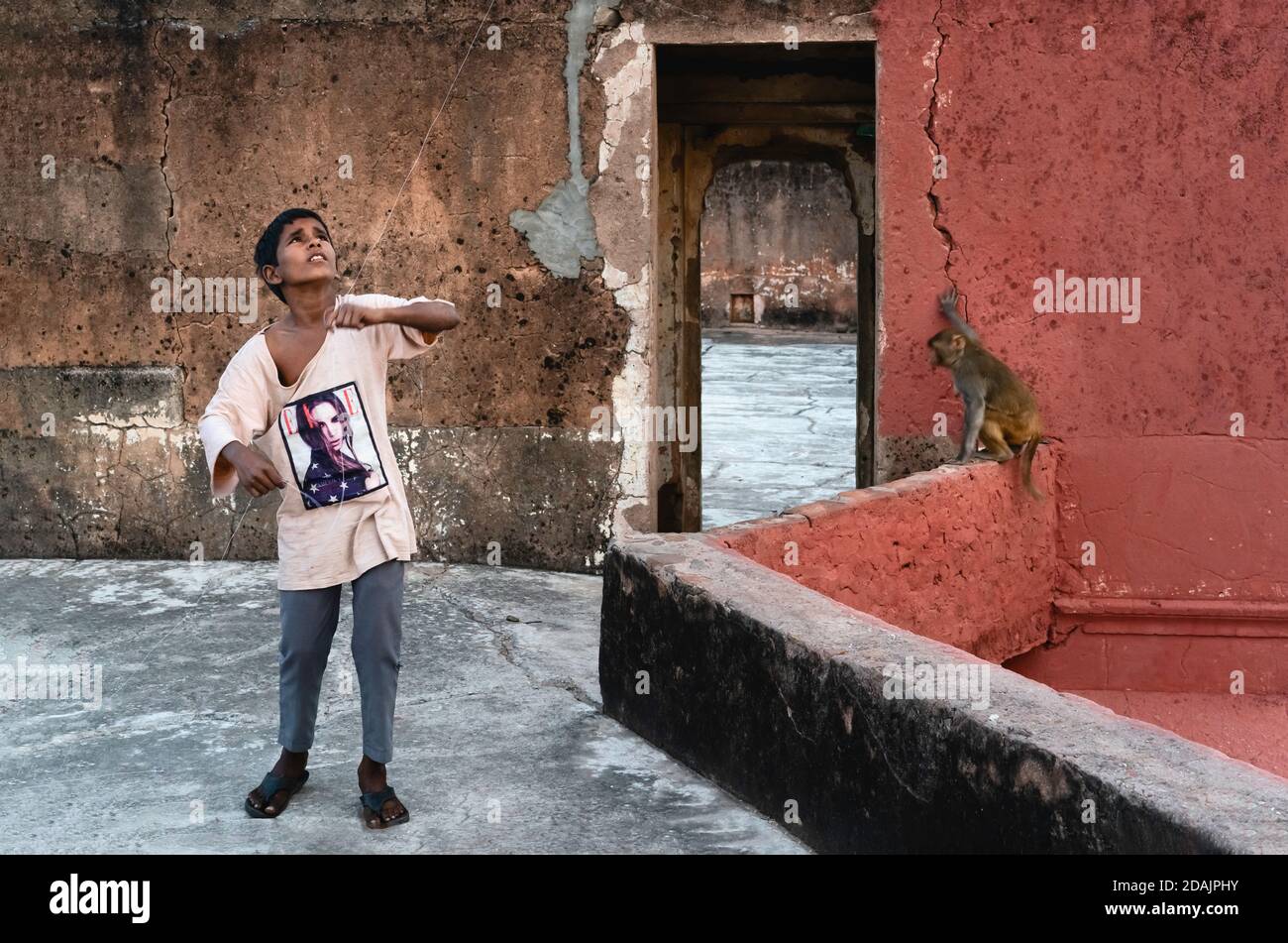 Young boy surrounded by ruins on rooftop flying kite (not in view) at dusk on November 09, 2019 in Jaipur, Rajasthan, India. Stock Photo