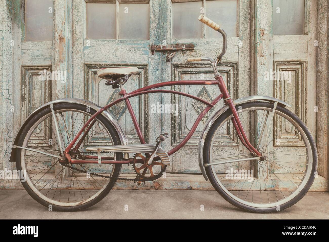 Vintage beach cruiser bicycle in front of antique wooden weathered doors  Stock Photo - Alamy