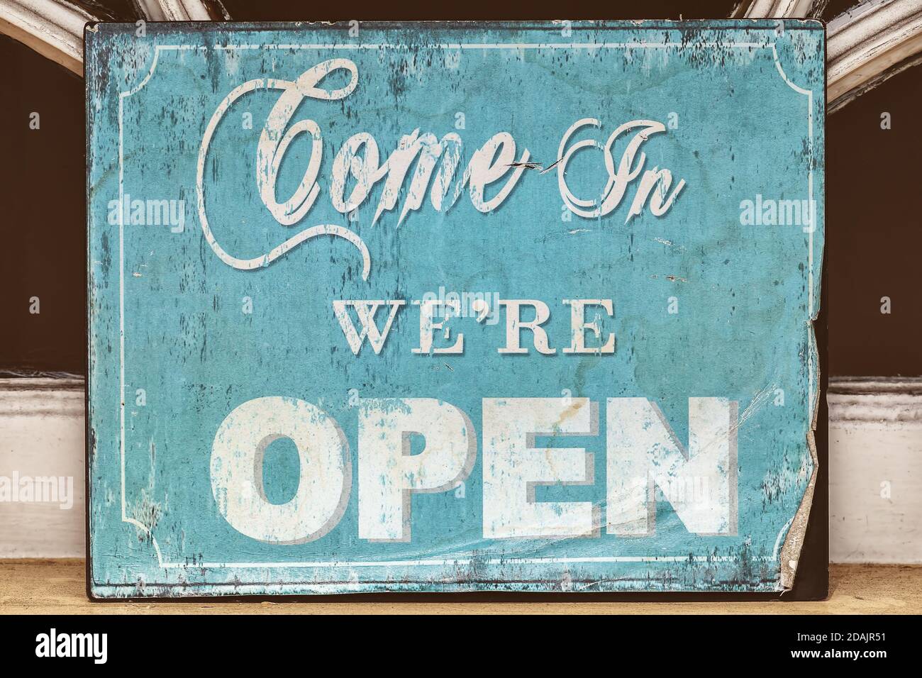 Weathered blue come in we're open sign Stock Photo