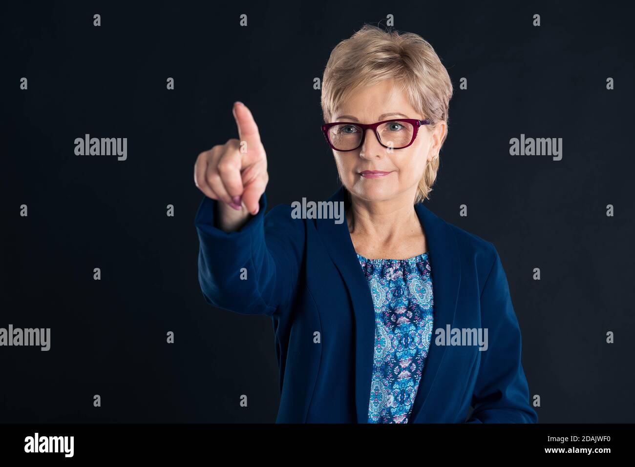Older blonde secretary pressing virtual button and similing Stock Photo