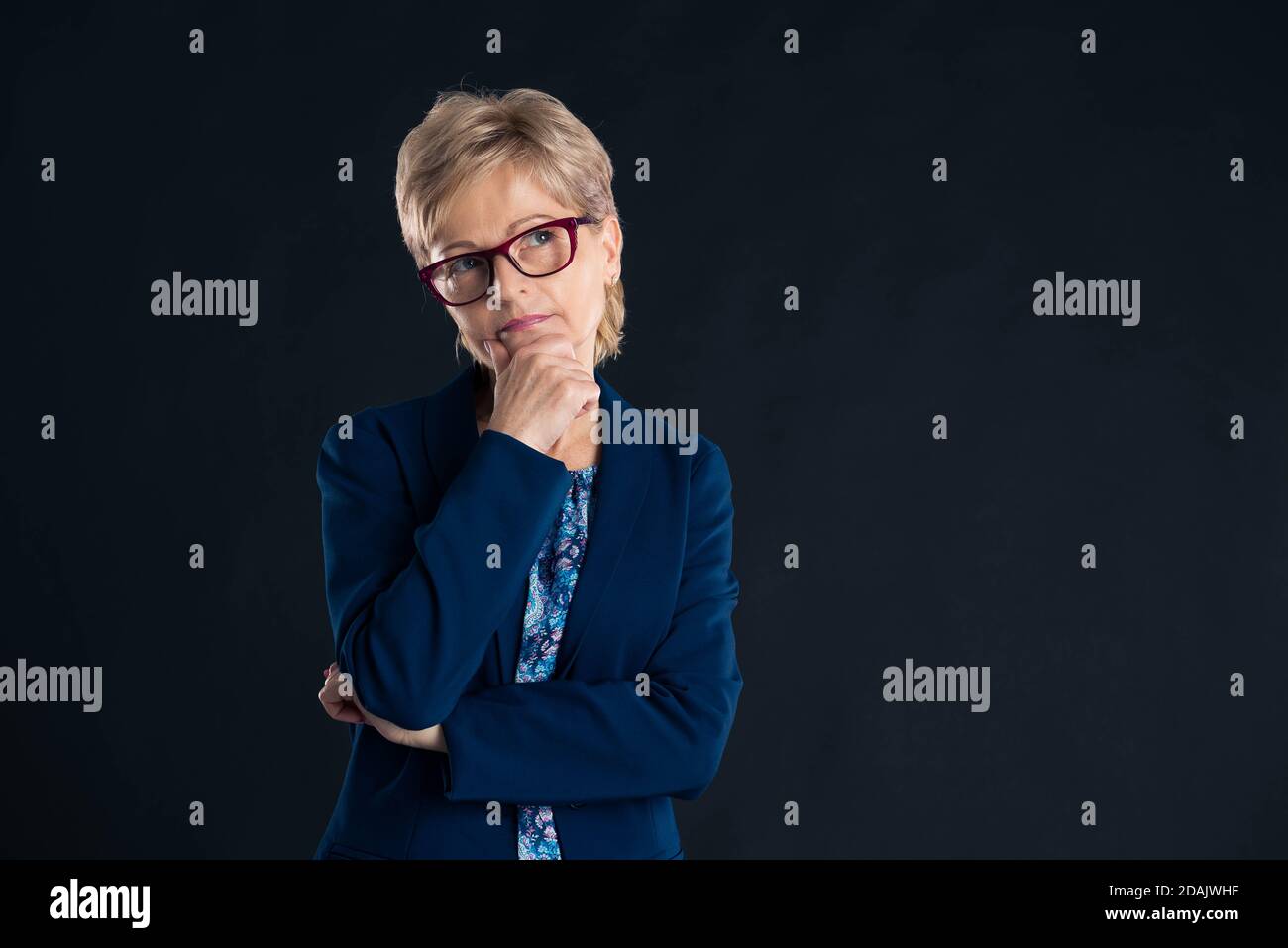 Portrait of an older secretary thinking of something wearing a blue jaket and glasses Stock Photo