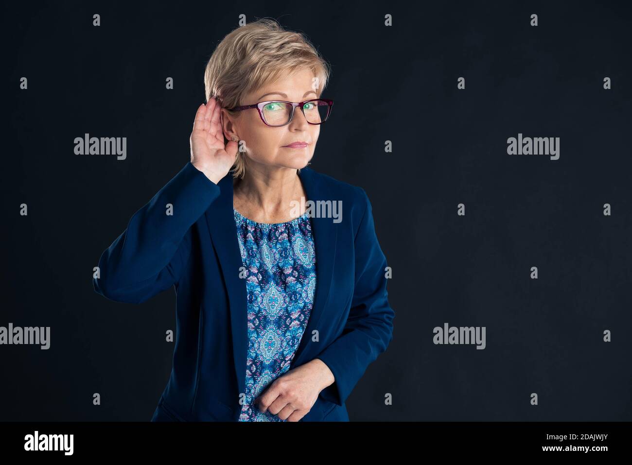 Senior secretary making what did you say gesture on a dark background Stock Photo