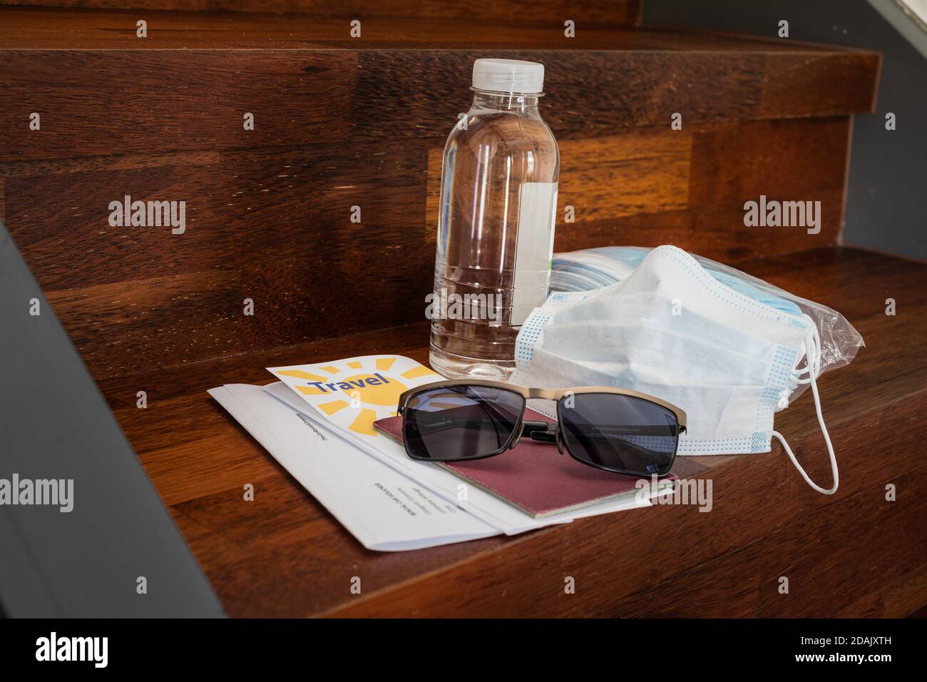 Traveling in times of corona virus concept: A pack of masks, a used mask, a bottle of disinfectant, a passport, travel documents, sunglasses and trave Stock Photo