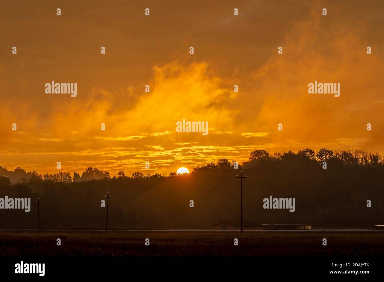 The colorful dawn of a new day in the early morning mists over the Tuscan countryside near Pisa, Italy Stock Photo