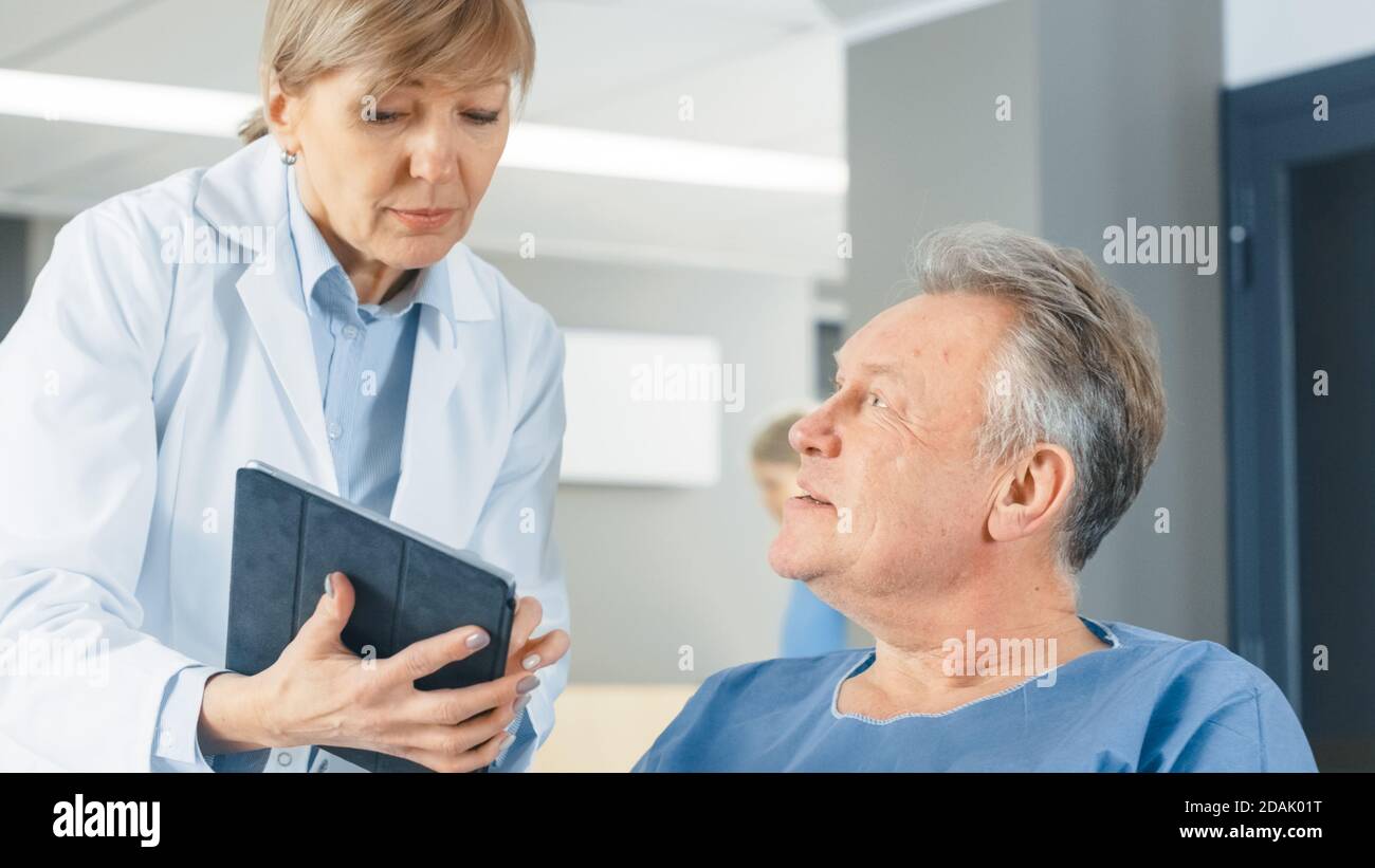 In the Hospital Female Doctor Shows Tablet Computer to Elderly 