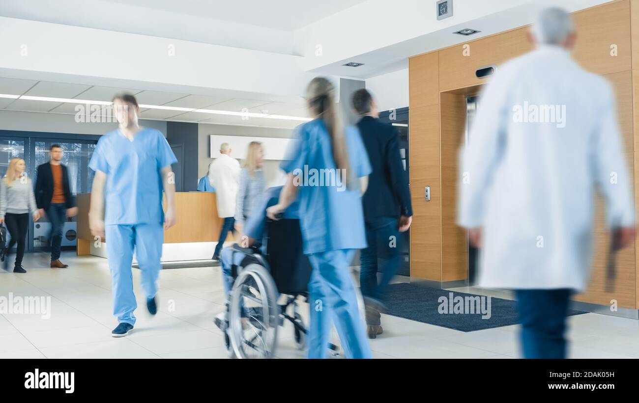 Hospital Lobby. Doctors, Nurses, Assistant Personnel and Patients Working and Walking in the Lobby of the Medical Facility. Stock Photo