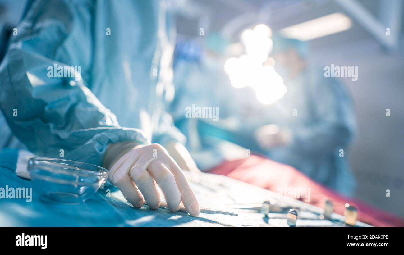 Close-up Shot in the Operating Room of Surgical Table with Instruments, Assistant Picks up Instruments for Surgeons During Operation. Surgery in Stock Photo