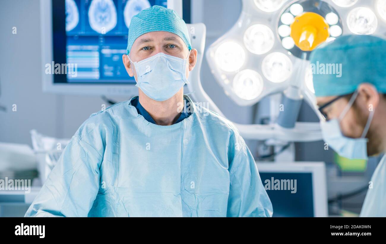 Portrait Shot in the Operating Room, of a Surgeon Looking into Camera During Operation. Professional Medical Doctors Performing Surgery. Stock Photo