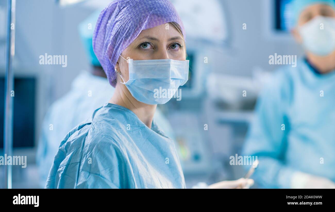 Portrait Shot of a Nurse Looking into Camera During Operation in the Operating Room. Professional Medical Doctors Performing Surgery. Stock Photo