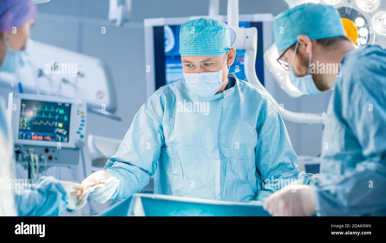 Shot in the Operating Room, Assistant Hands out Instruments to Surgeons During Operation. Surgeons Perform Operation. Professional Medical Doctors Stock Photo
