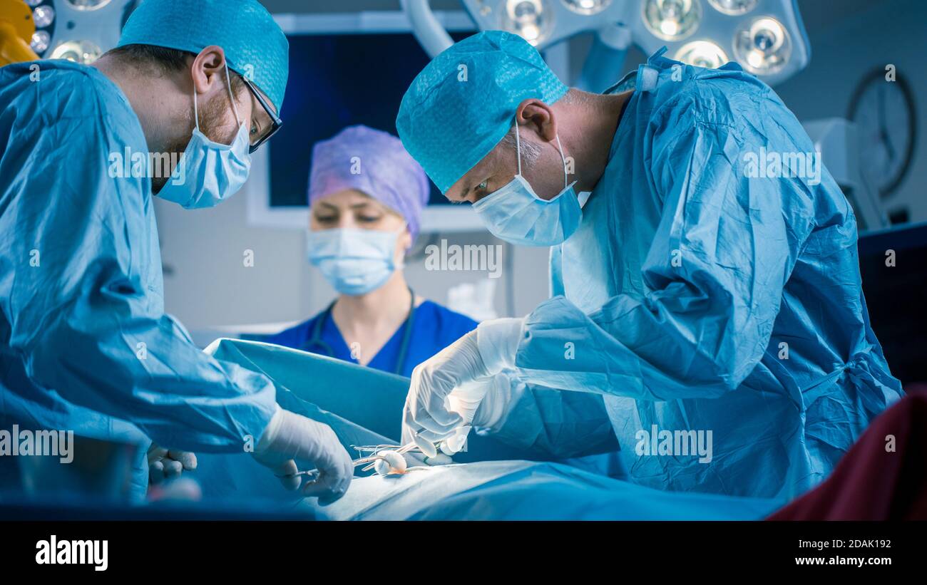 In the Hospital Operating Room Diverse Team of Professional Surgeons and Nurses Suture Wound after Successful Surgery. Stock Photo