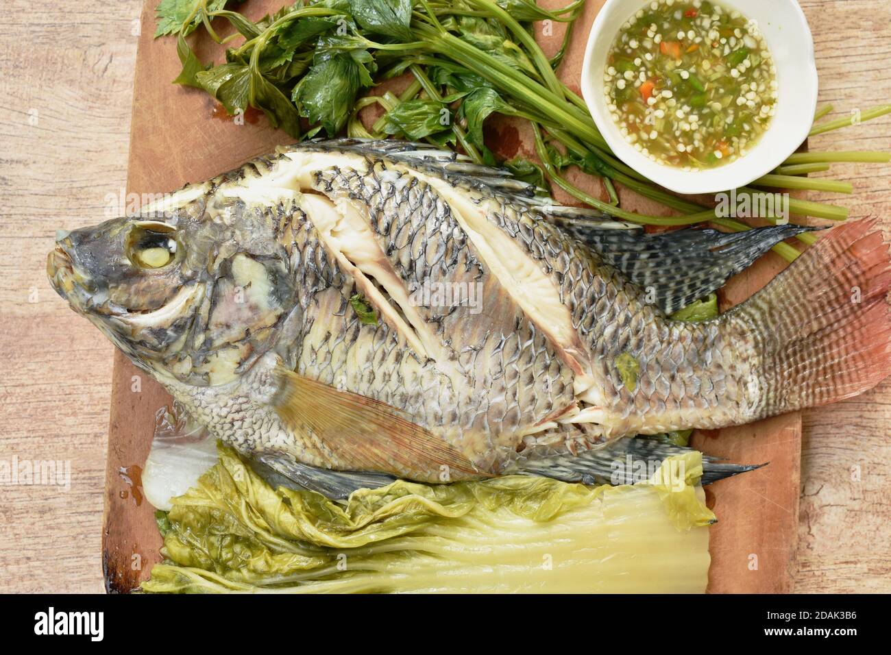 steamed mango fish with vegetable dipping spicy sauce on wooden chop ...