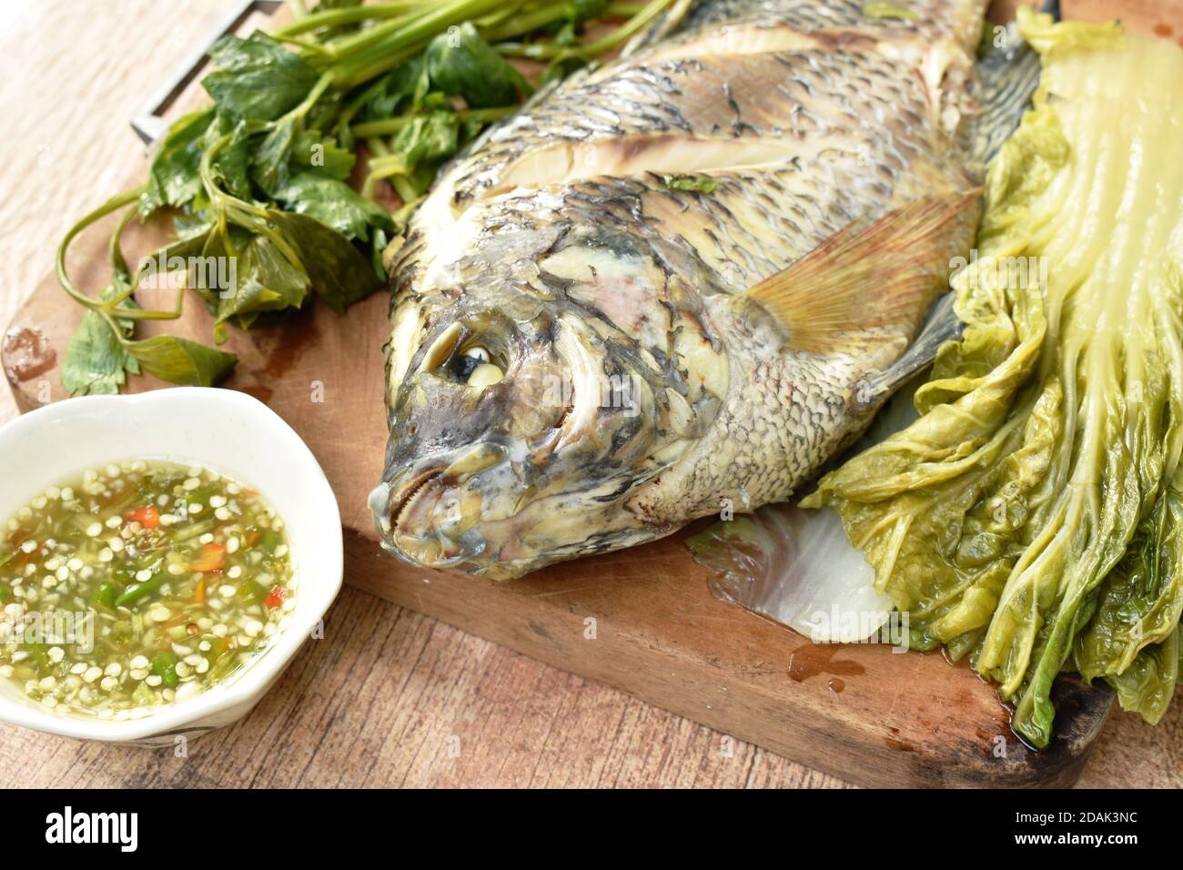 steamed mango fish with vegetable dipping spicy sauce on wooden chop ...