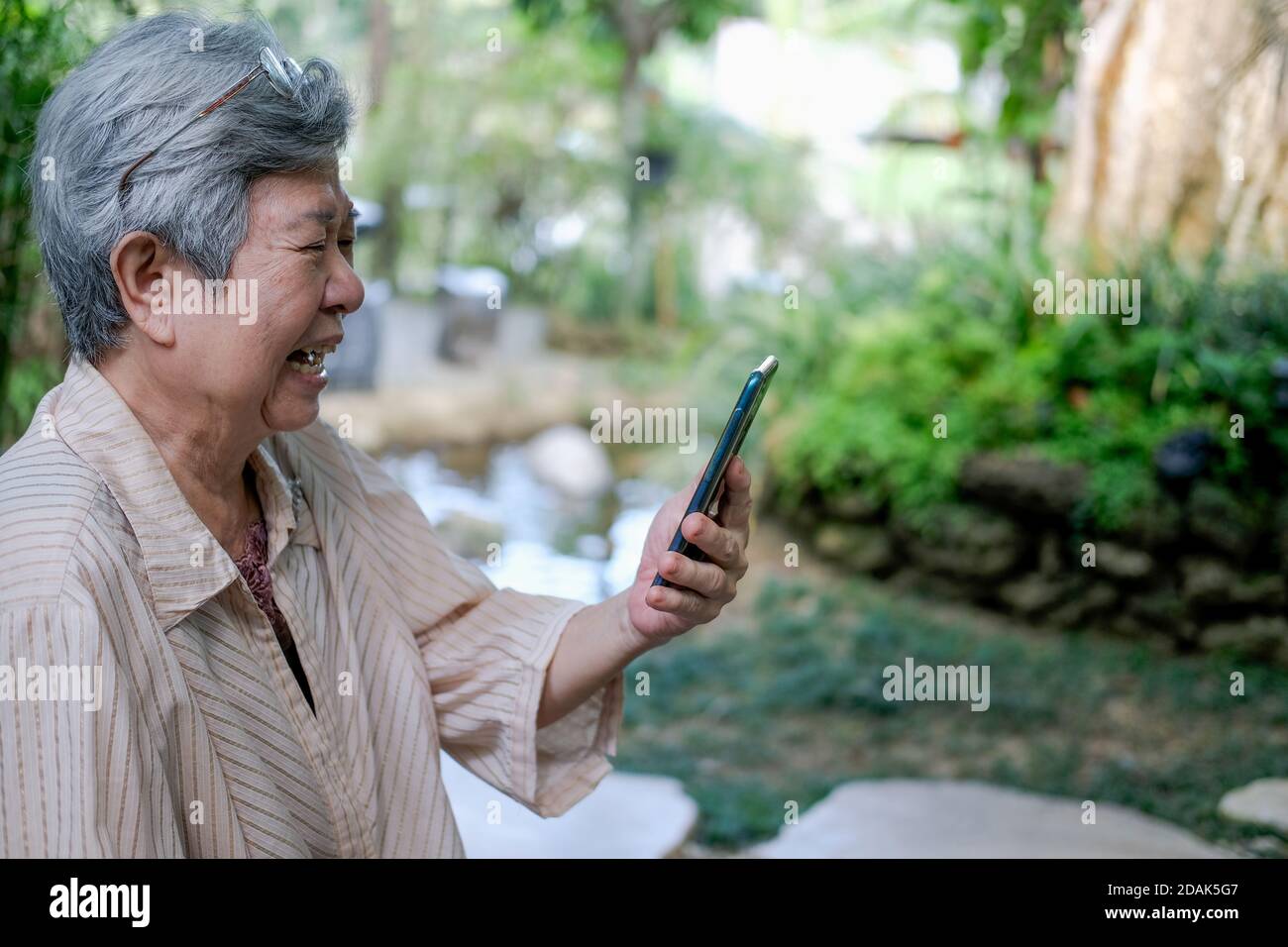 sad upset asian old asian elderly senior elder woman talking on video call on smart mobile phone Stock Photo
