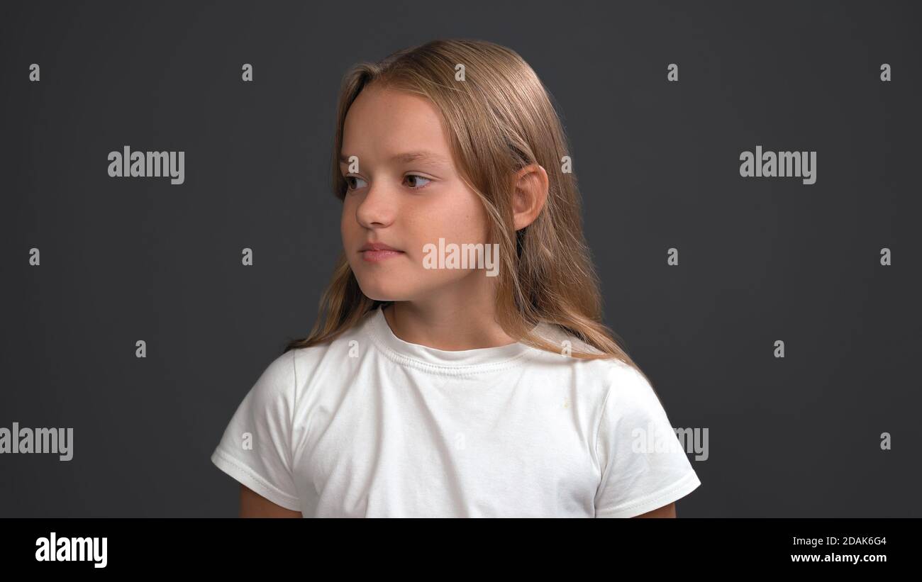 Nice teen girl seriously looking on copy space at left side. Pretty Caucasian girl wearing white t-shirt. Head and shoulders portrait. Isolated on Stock Photo
