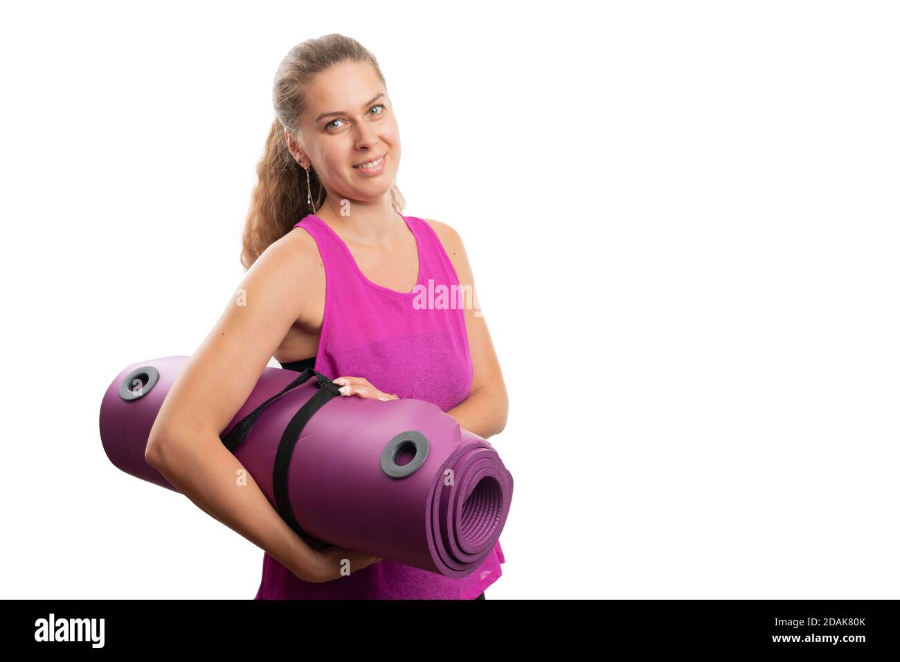 Friendly adult sporty woman model holding yoga mat wearing workout pink tanktop as active sportive lifestyle concept isolated on white background with Stock Photo