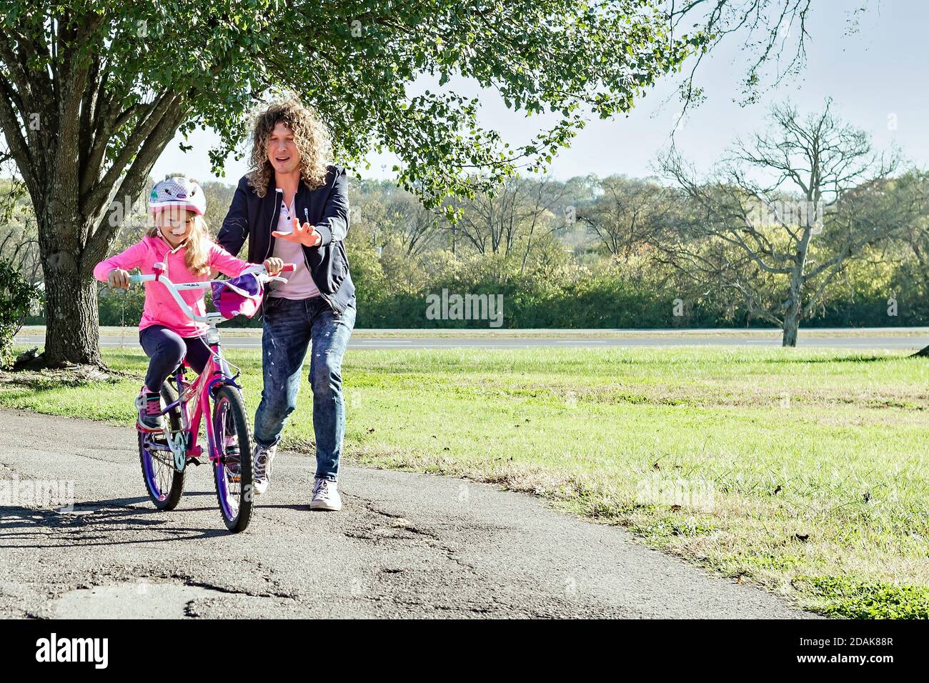Dad teaches his young daughter to ride a two-wheeler bicycle Stock ...