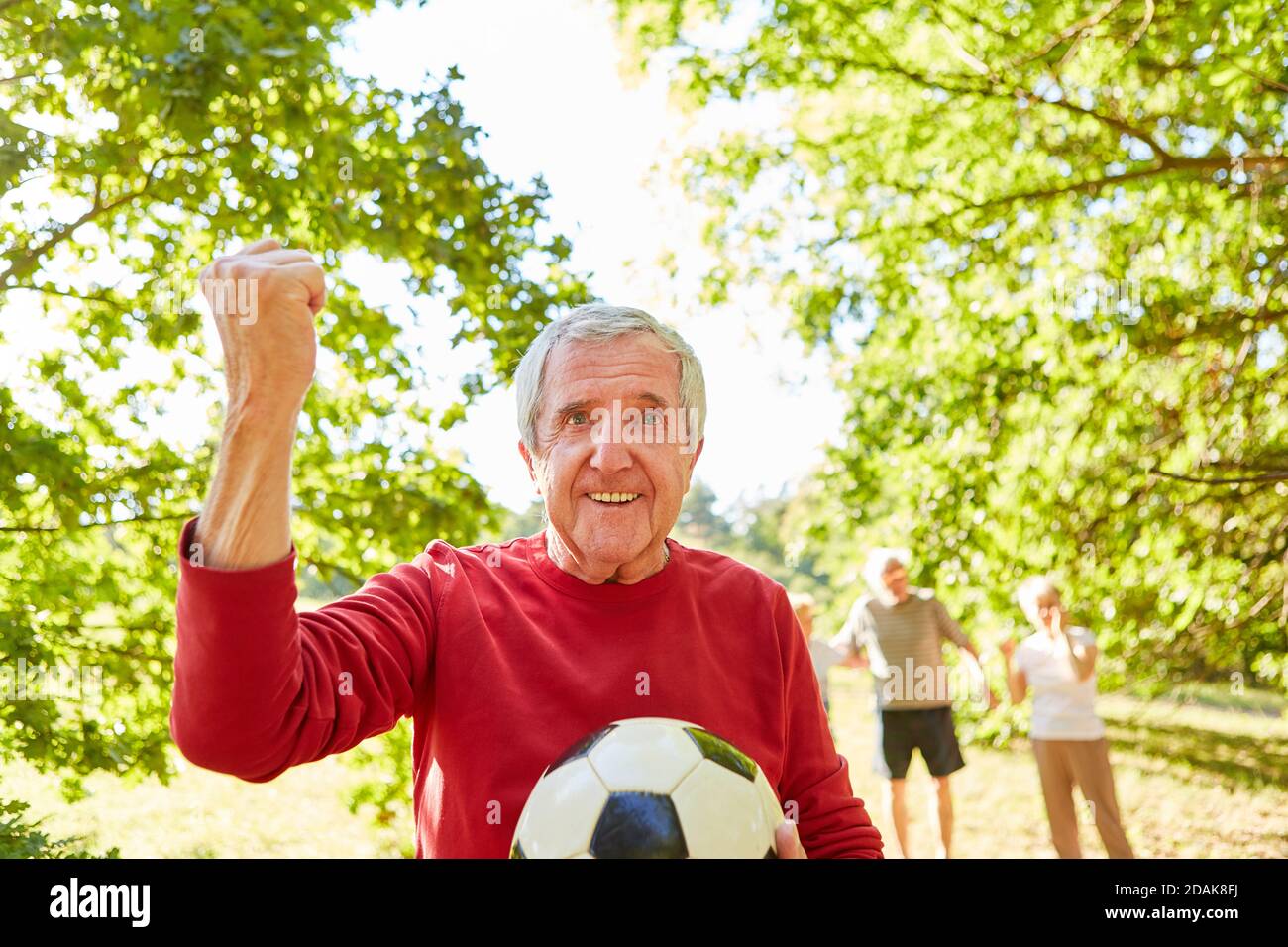 Vital senior man with clenched fist as the winner after a soccer game in the park Stock Photo