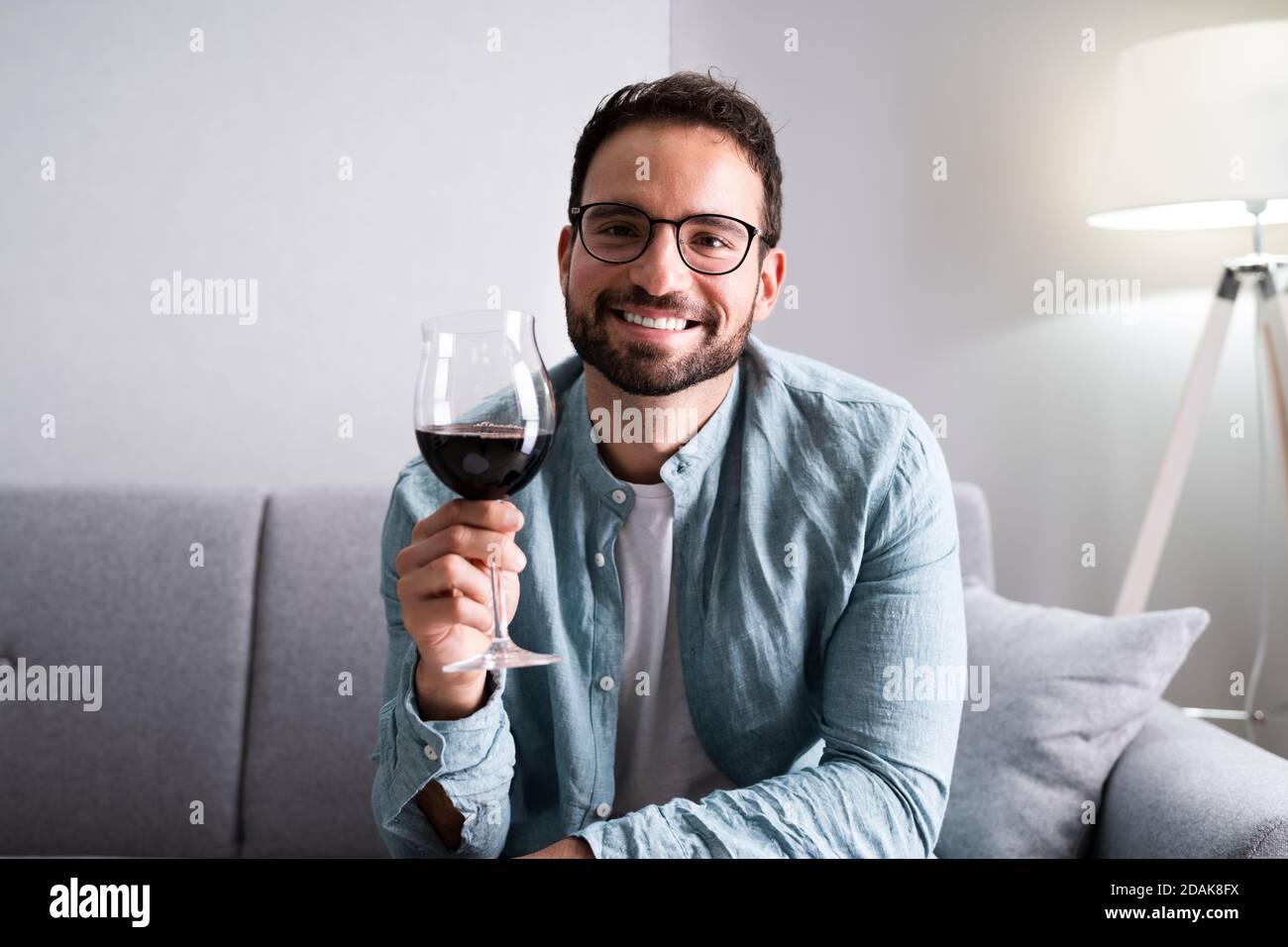 Man Drinking Red Wine In Video Conference At Home Stock Photo