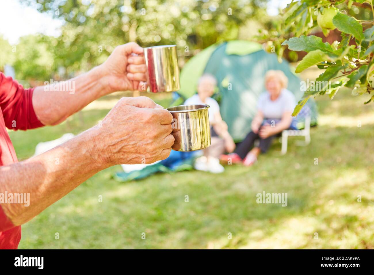 Man brings two cups of coffee in the morning for breakfast at the campsite Stock Photo