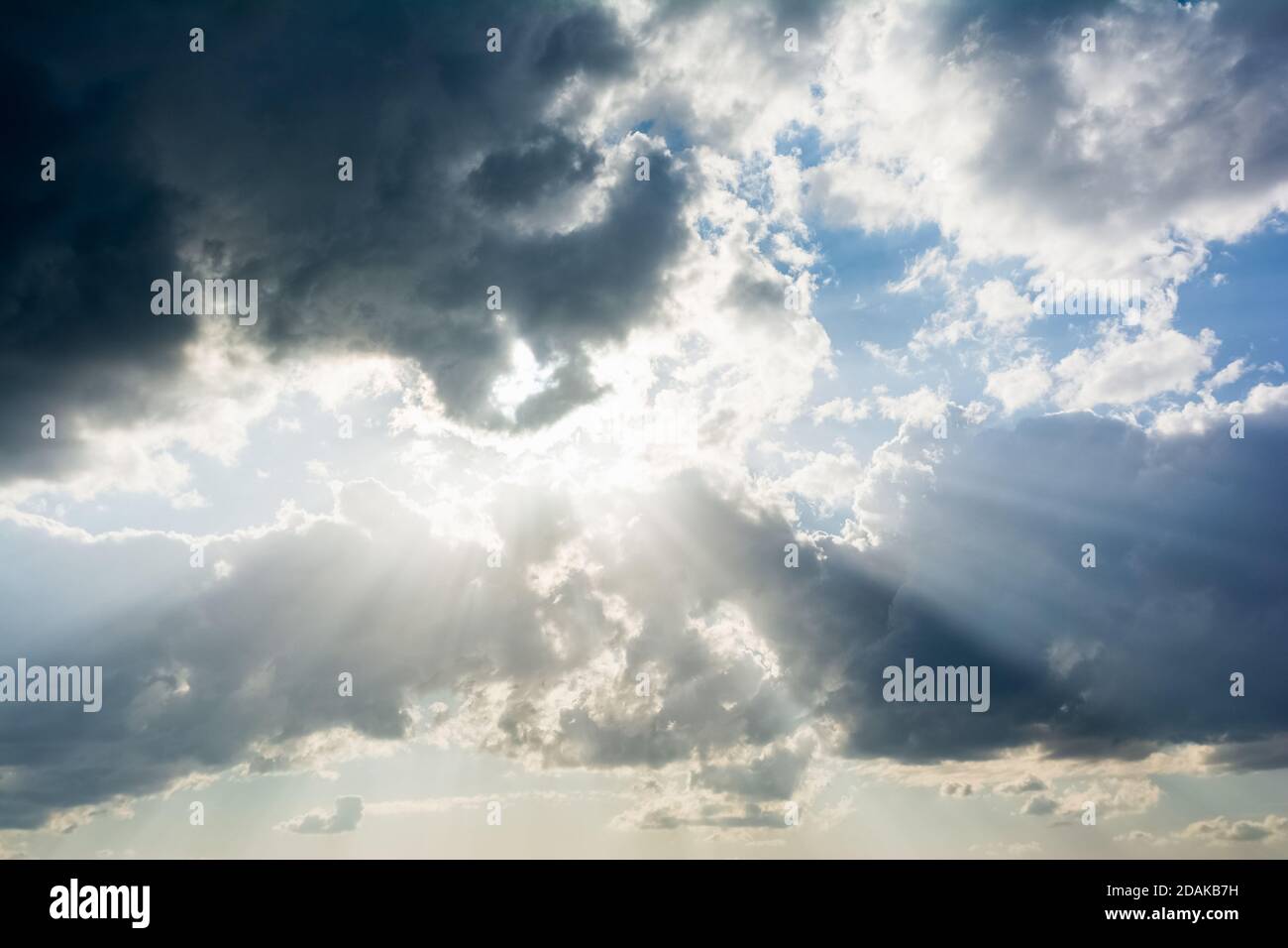 Beautiful dramatic sky with sun rays shining through dark clouds for