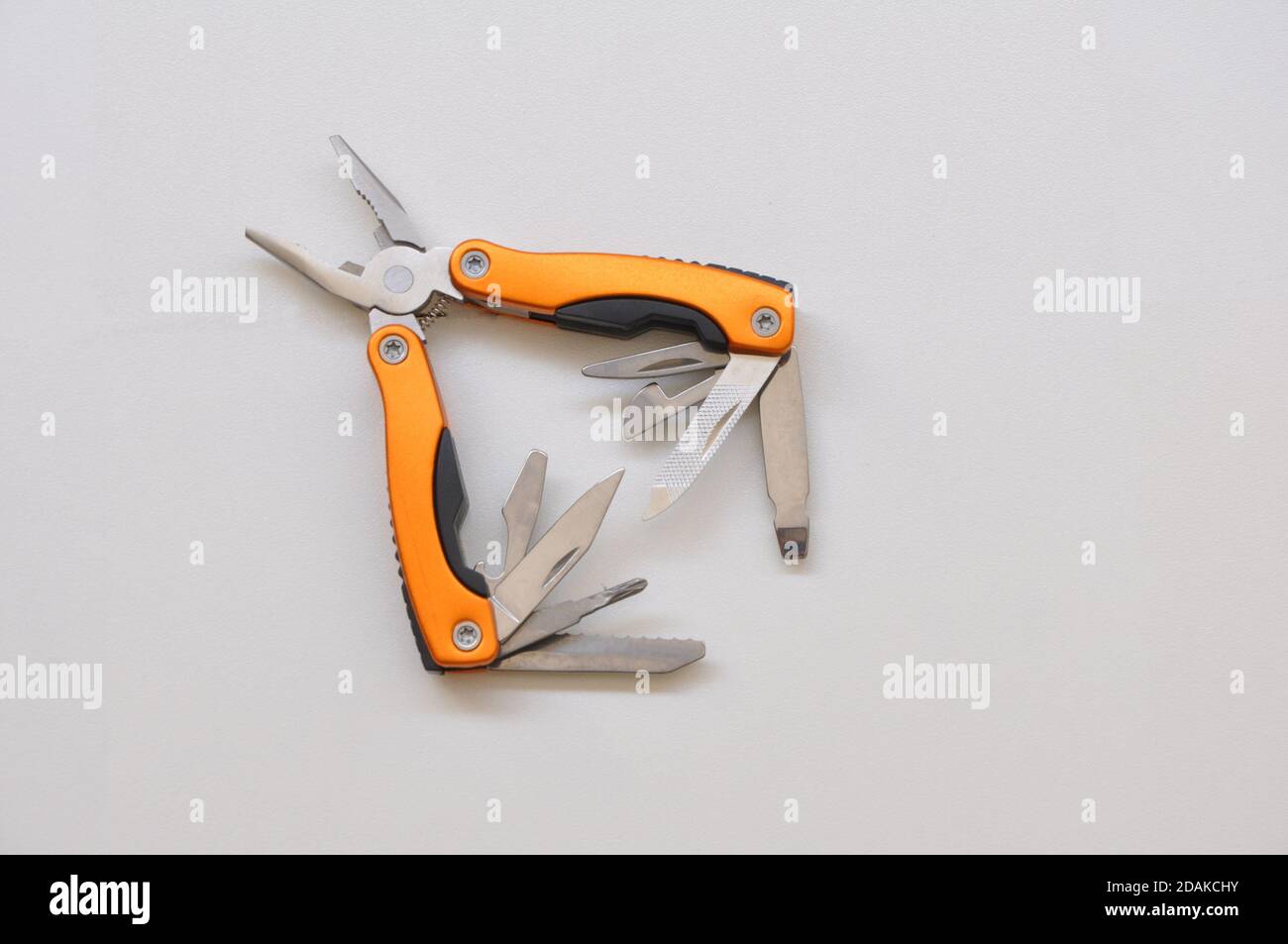Pliers, multifunctional with functional tools, for use at home, in orange color with white background, copy space, side view Stock Photo