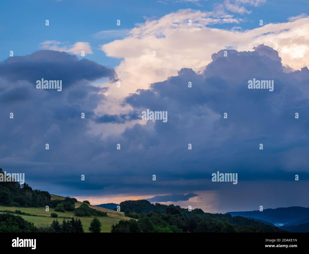 Massive storm clouds in the sky over hilly landscape Stock Photo