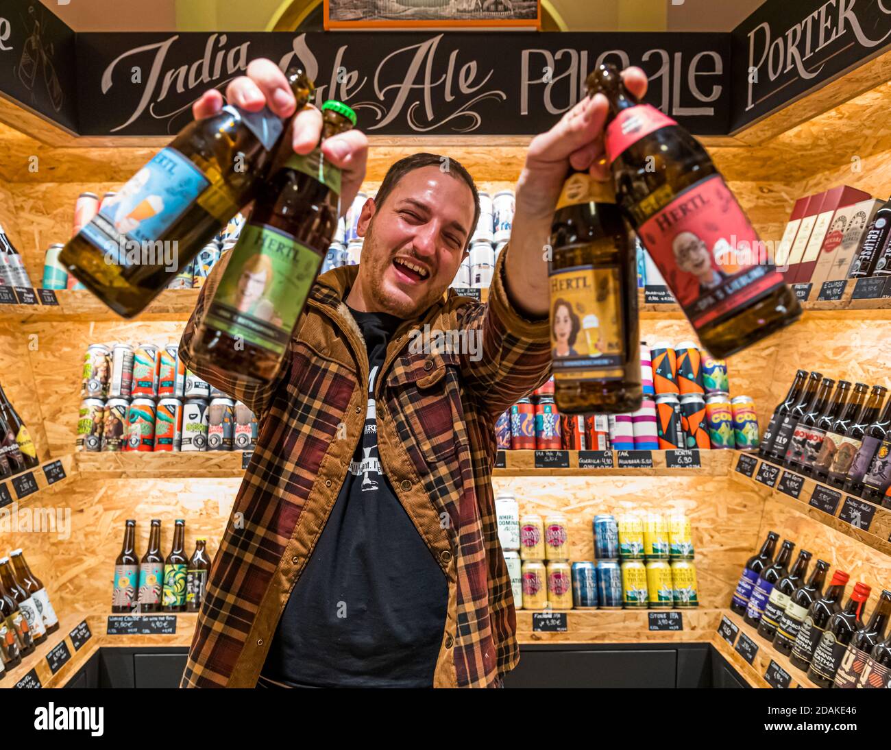 With great enthusiasm: David Hertl with beer from his own family brewery and surrounded by beers from all over the world. Hertl Beer Boutique in Bamberg, Germany Stock Photo