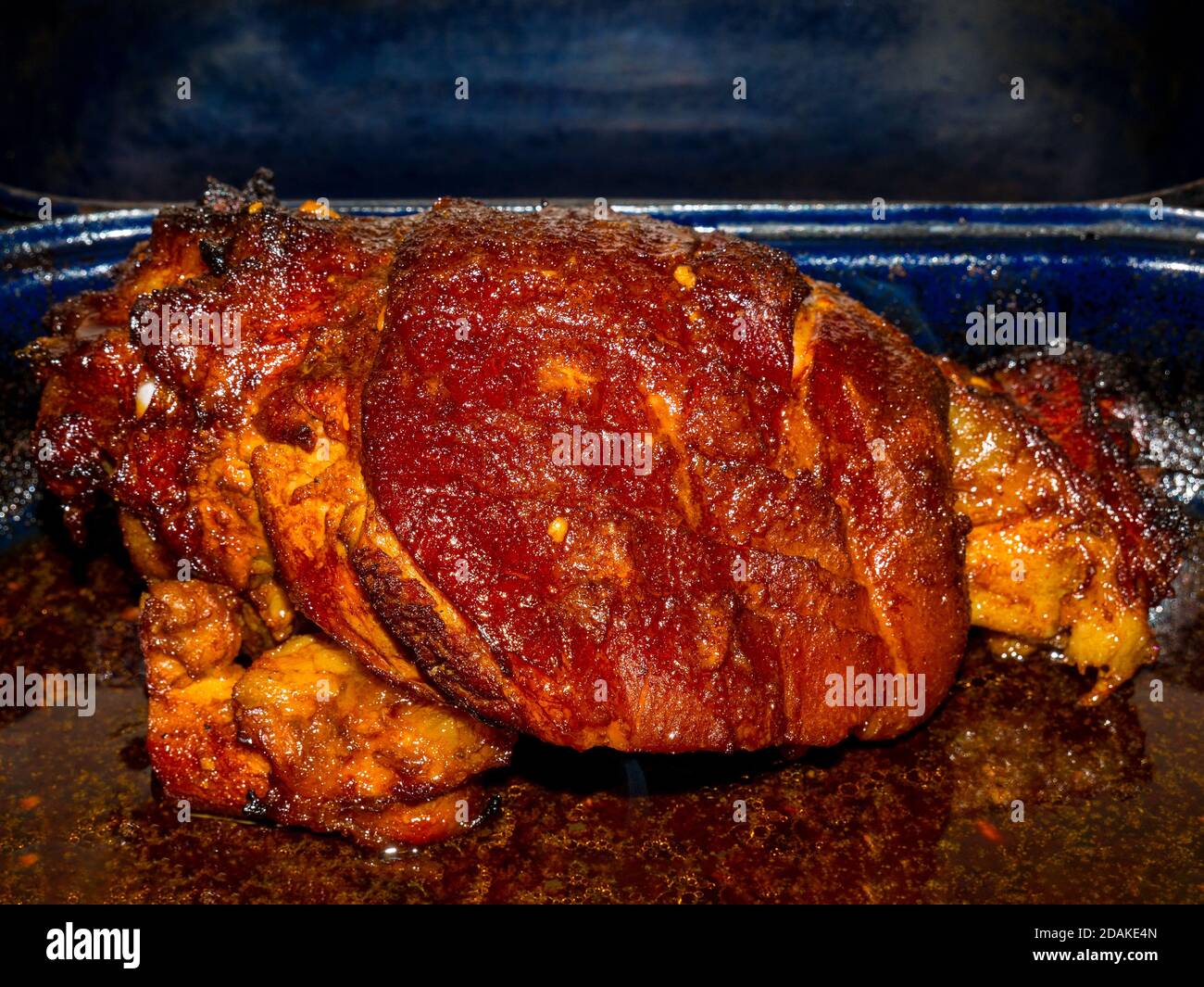 Roasted pork knuckle in a roasting pan with lots of baked fatty juice Stock Photo