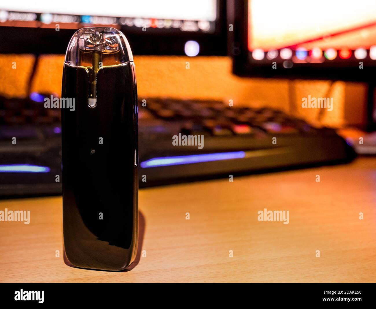 Electronic cigarette - the so-called POD system for vaping, standing on  desk in front of blurry backlit keyboard and PC monitors in background  Stock Photo - Alamy