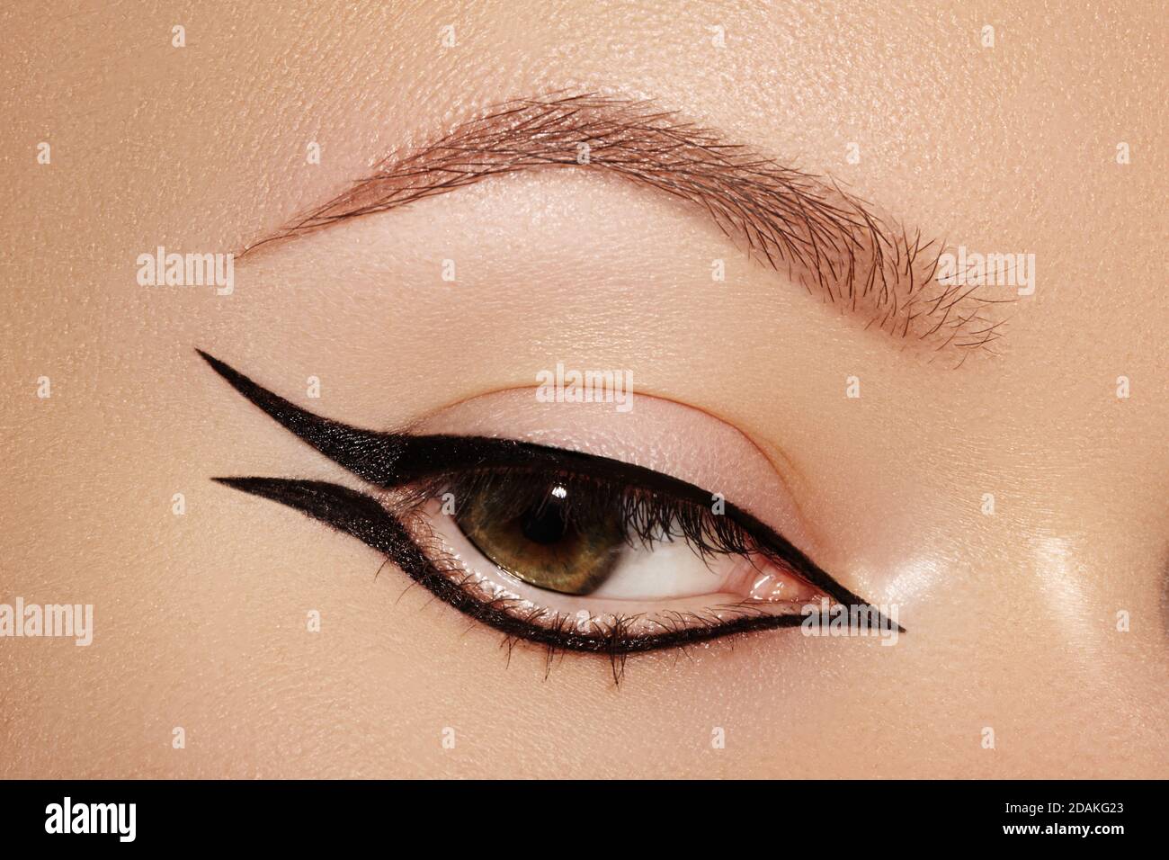 Beautiful macro shot of female eye with fashion black eyeliner makeup. Perfect graphic liner shape, minimalism style visage. Cosmetics and make-up. Cl Stock Photo