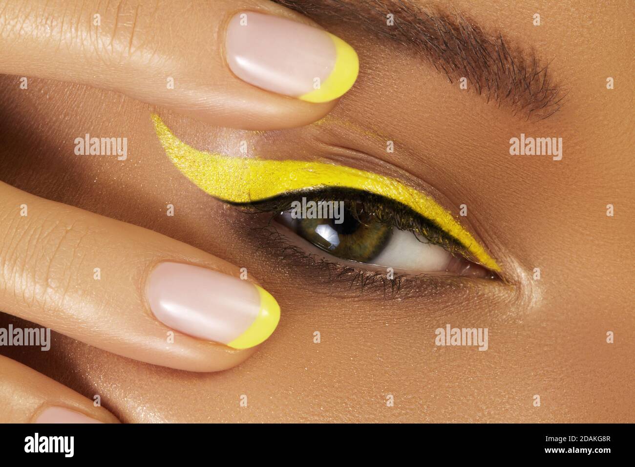 Beautiful macro close-up of female Eye with bright yellow Eyeliner Makeup. Neon Disco make-up and Fashion Manicure. Summer beauty styleCloseup macro s Stock Photo