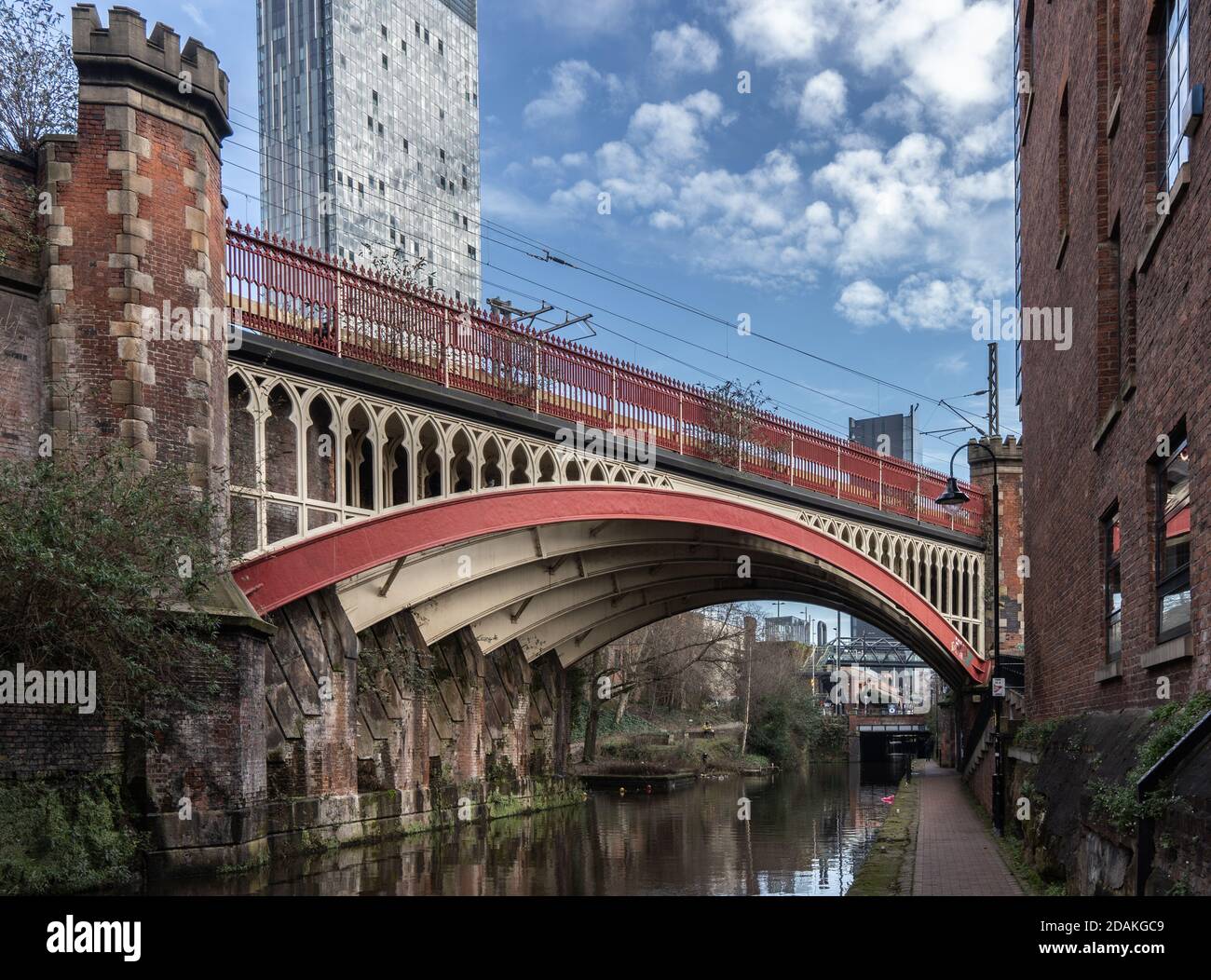 Red Victorian railway bridge over the Rochdale Canal in central Manchester with the Beetham Tower in the background Stock Photo