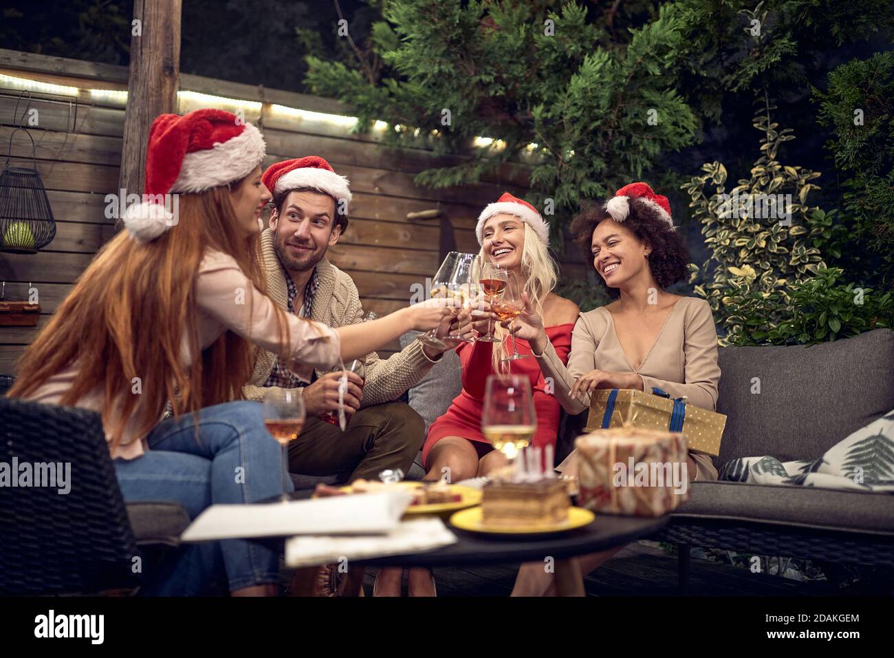 group of  young adults celebrating with santa clause hats, toasting, drinking wine Stock Photo