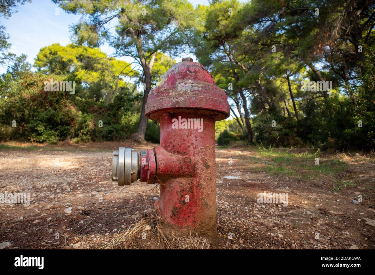 Fire protection concept. Firefighting public system, fire hydrant rusty metal red color outdoors in nature background. Old extinguisher with plug mean Stock Photo