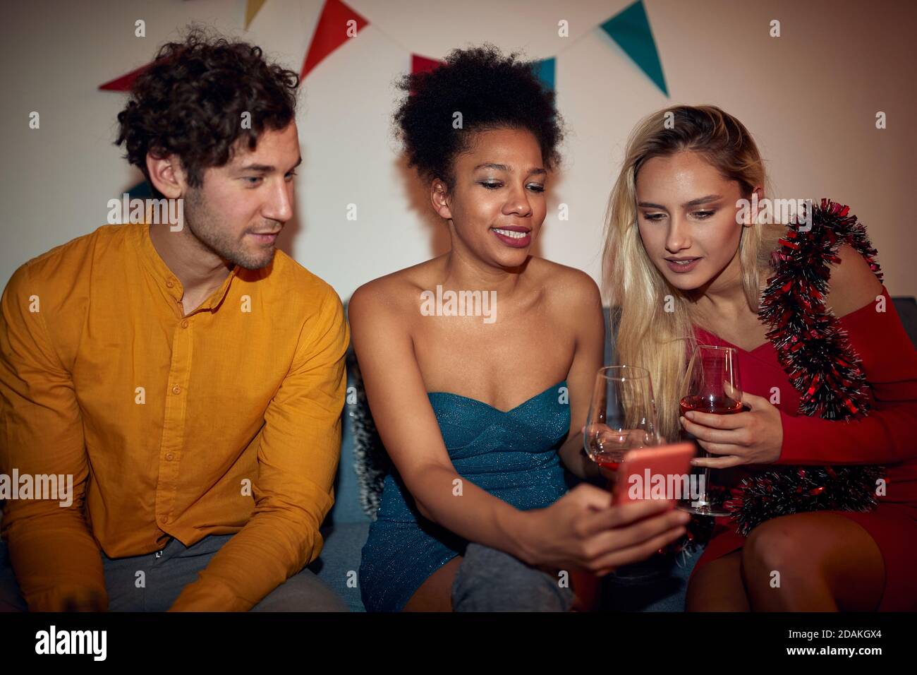 young  afro-american female showing content on her cell phone to a caucasian couple Stock Photo
