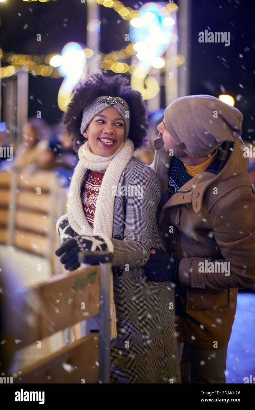 A young couple in moment of closeness at ice rink on a beautiful night. Skating, closeness, love, together Stock Photo