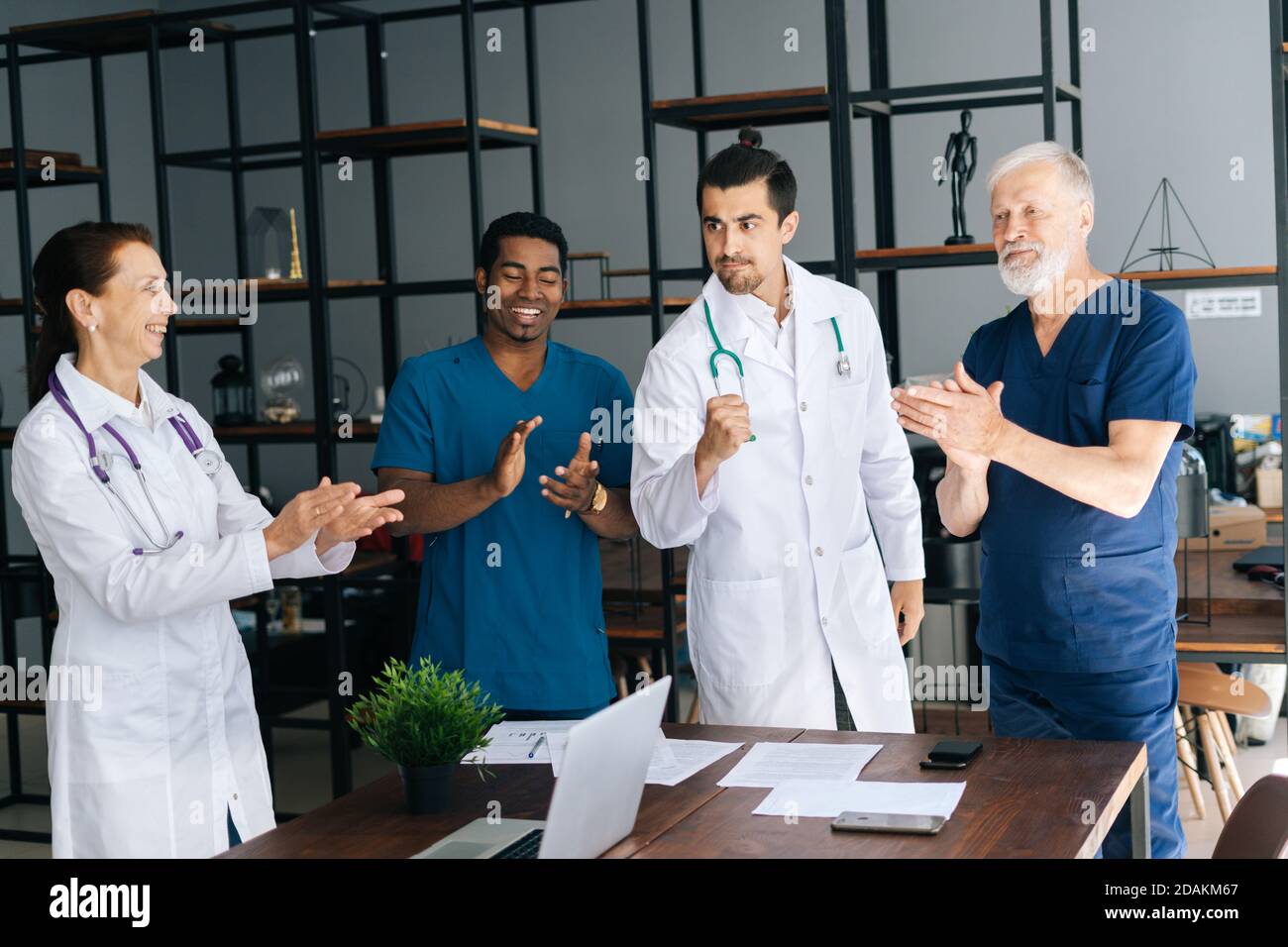 Successful skilled young doctor getting team applause in light office room at modern hospital.  Stock Photo
