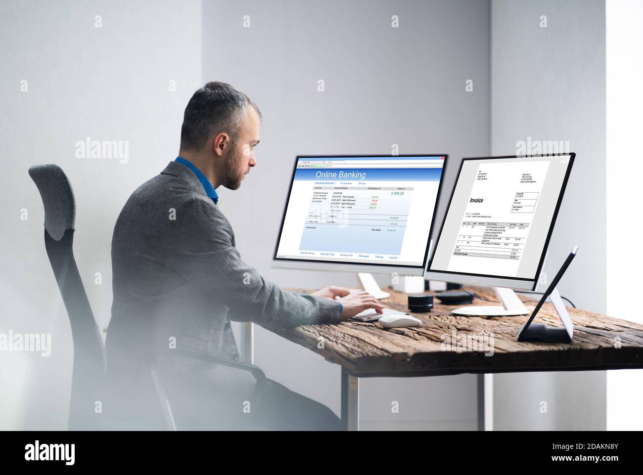 Young Businessman Looking At Invoice While Doing Online Banking On Computer Stock Photo