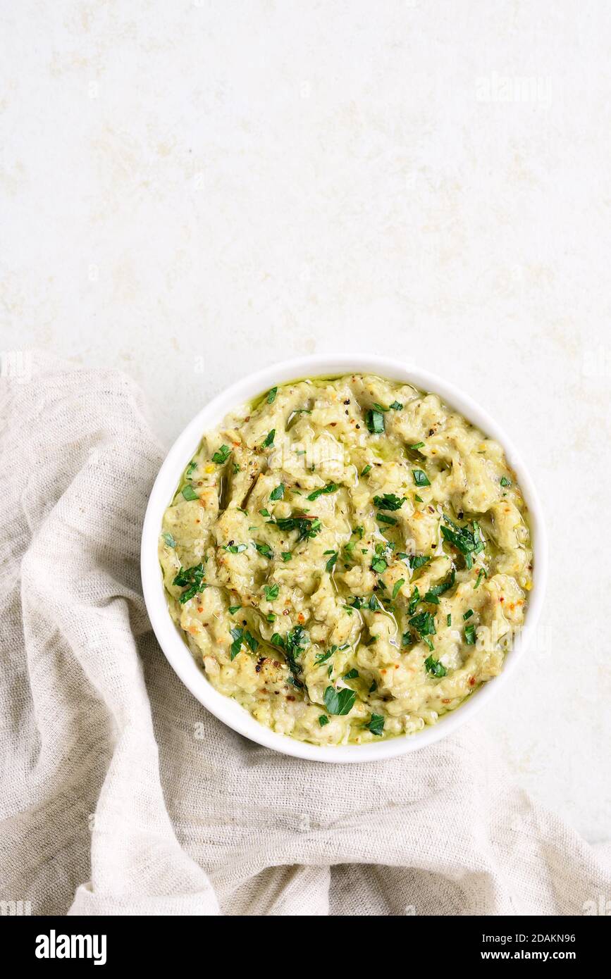 Baba ganoush (roasted eggplant dip) in bowl over light stone background with free text space. Vegetarian vegan food concept. Top view, flat lay Stock Photo