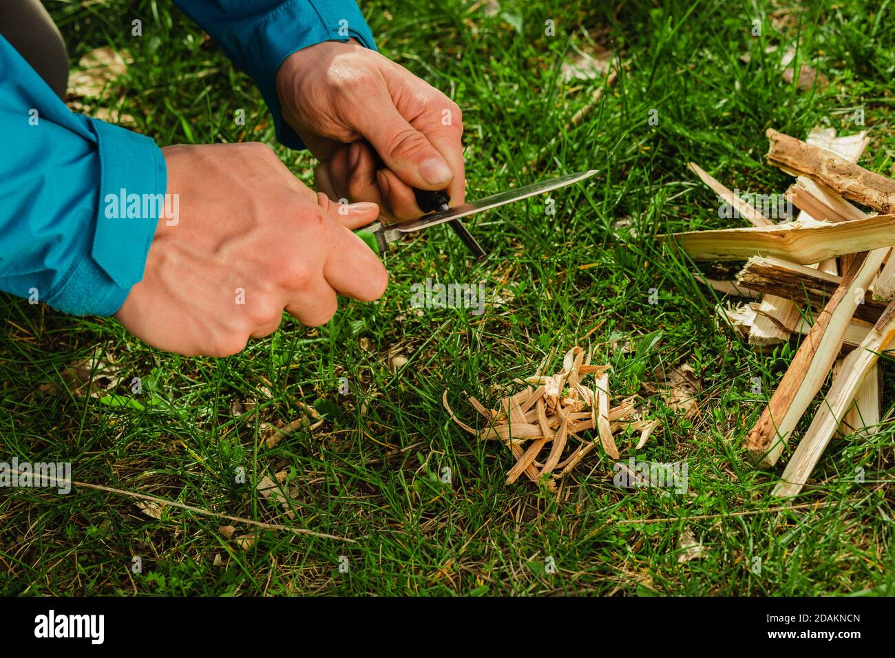 male hand using survival knife with firestarter. Ways to start a fire without matches Stock Photo